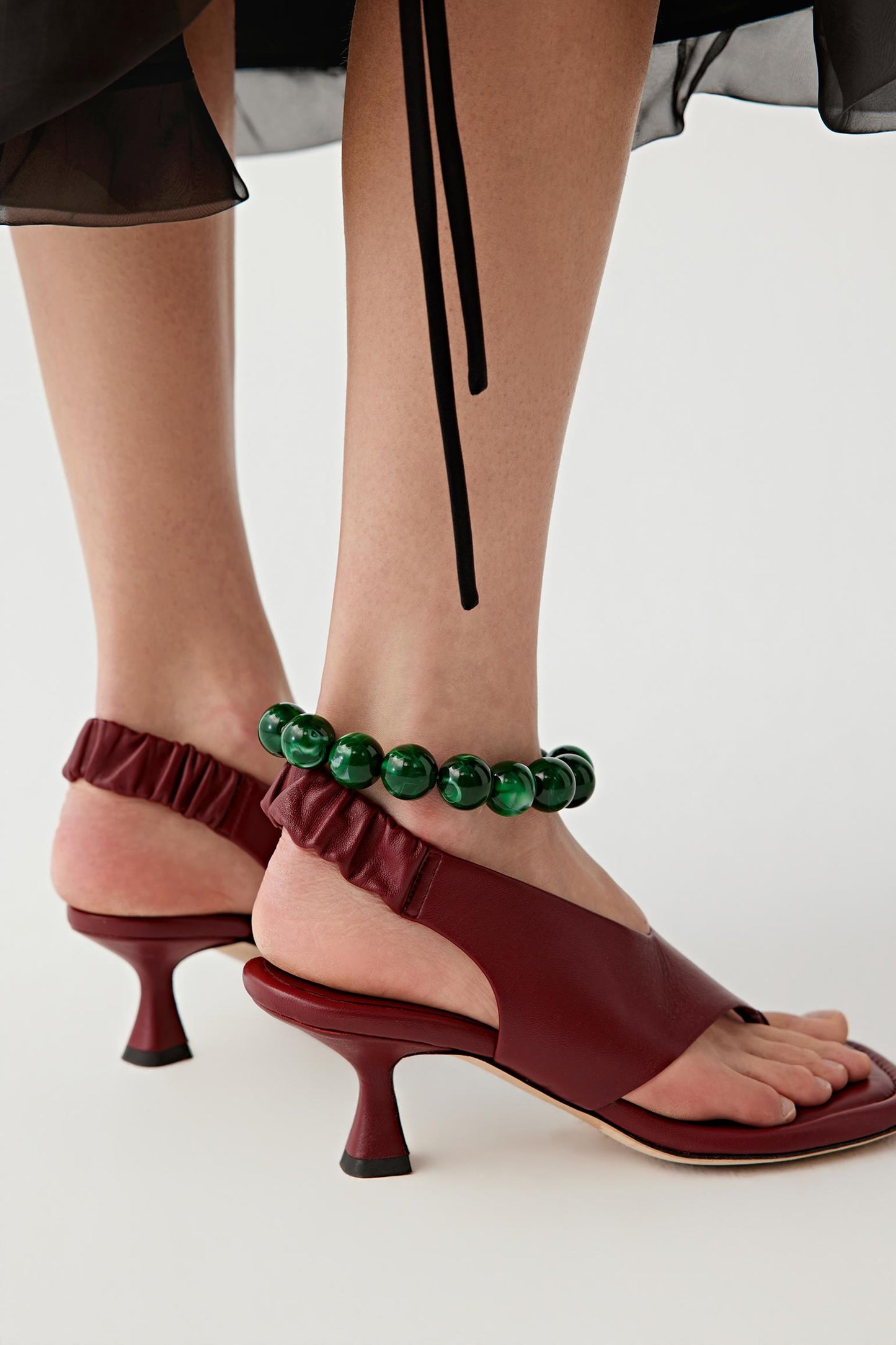 Three-quarter rear view focusing on the back of the sandals, highlighting the slingback construction, heel shape and the way the leather strap wraps around the foot while maintaining a clean, structured silhouette