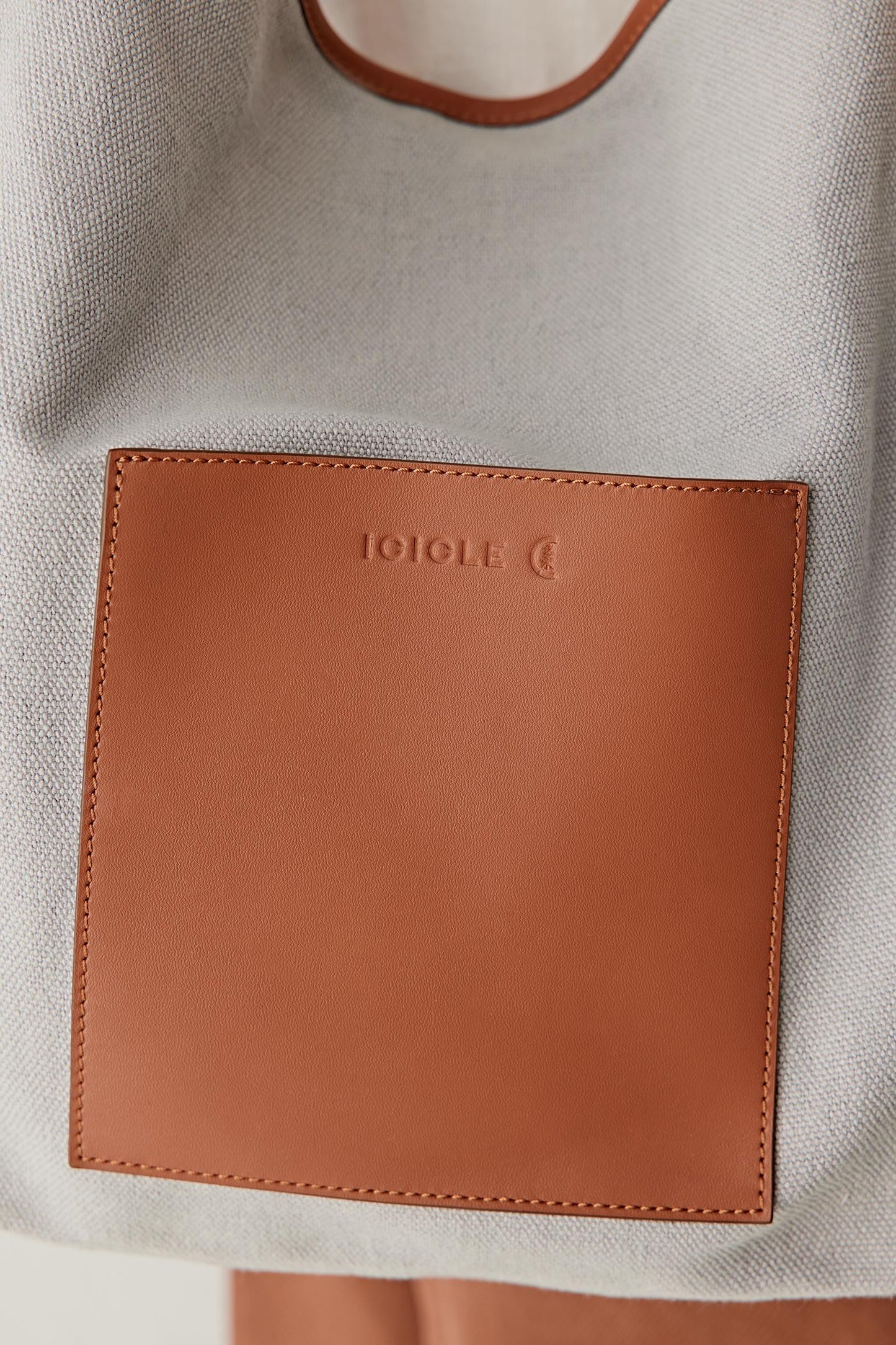 Close-up of leather panel showing smooth surface, stitching lines, edge finishing and contrast with textured fabric
