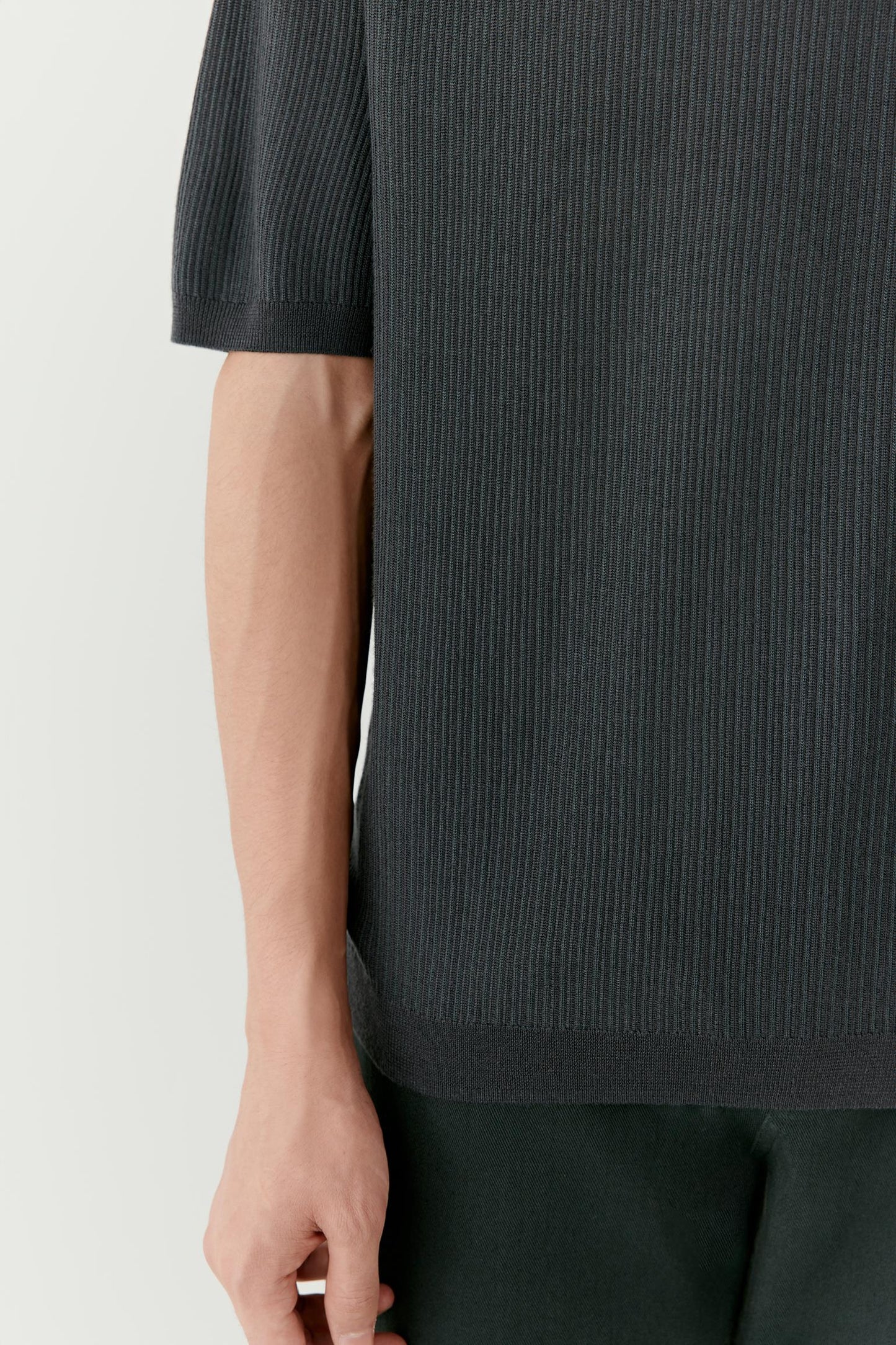 Close-up of the sleeve and side body highlighting the smooth, lightweight wool knit and clean finishing at the edges.