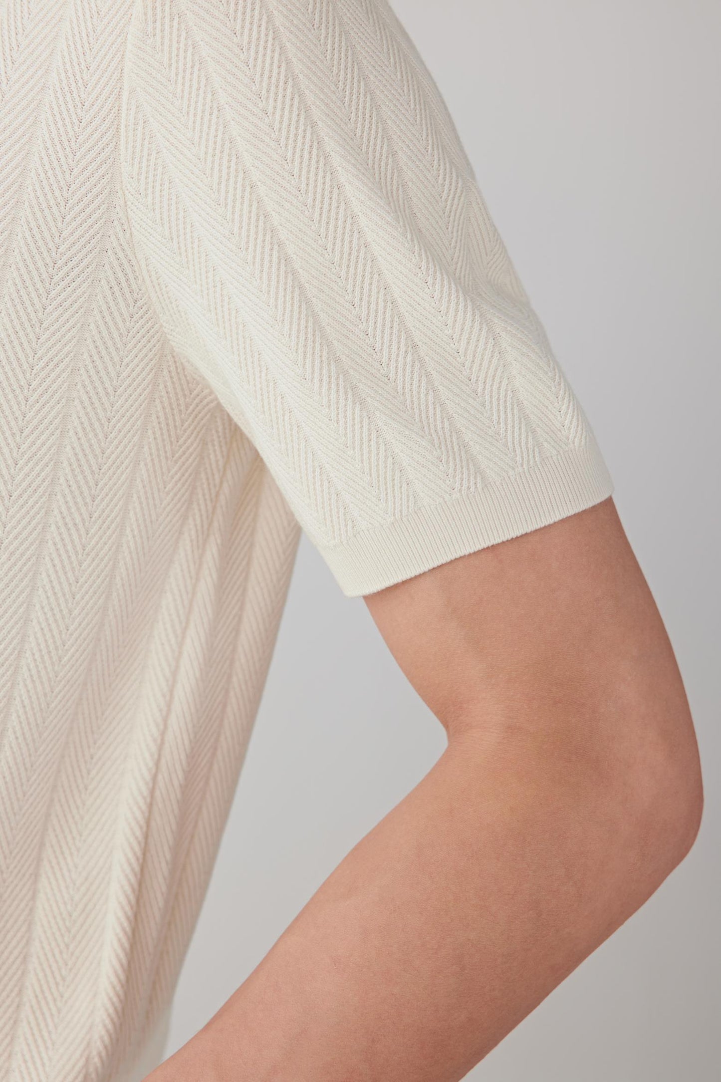 Detail view of the sleeve edge, highlighting the soft handle and fine construction of the silk yarn.