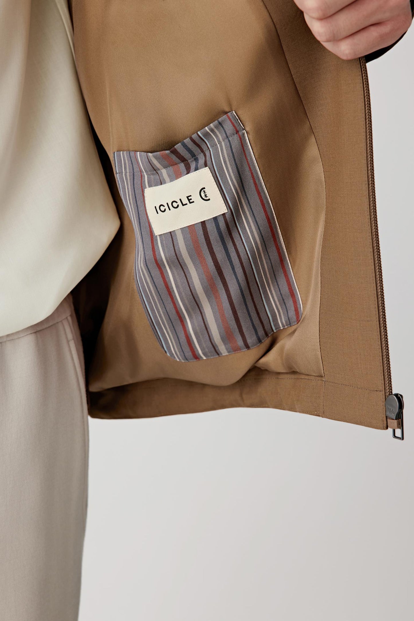 Close-up of a brown jacket with a striped pocket square and 'ICICLE' label.