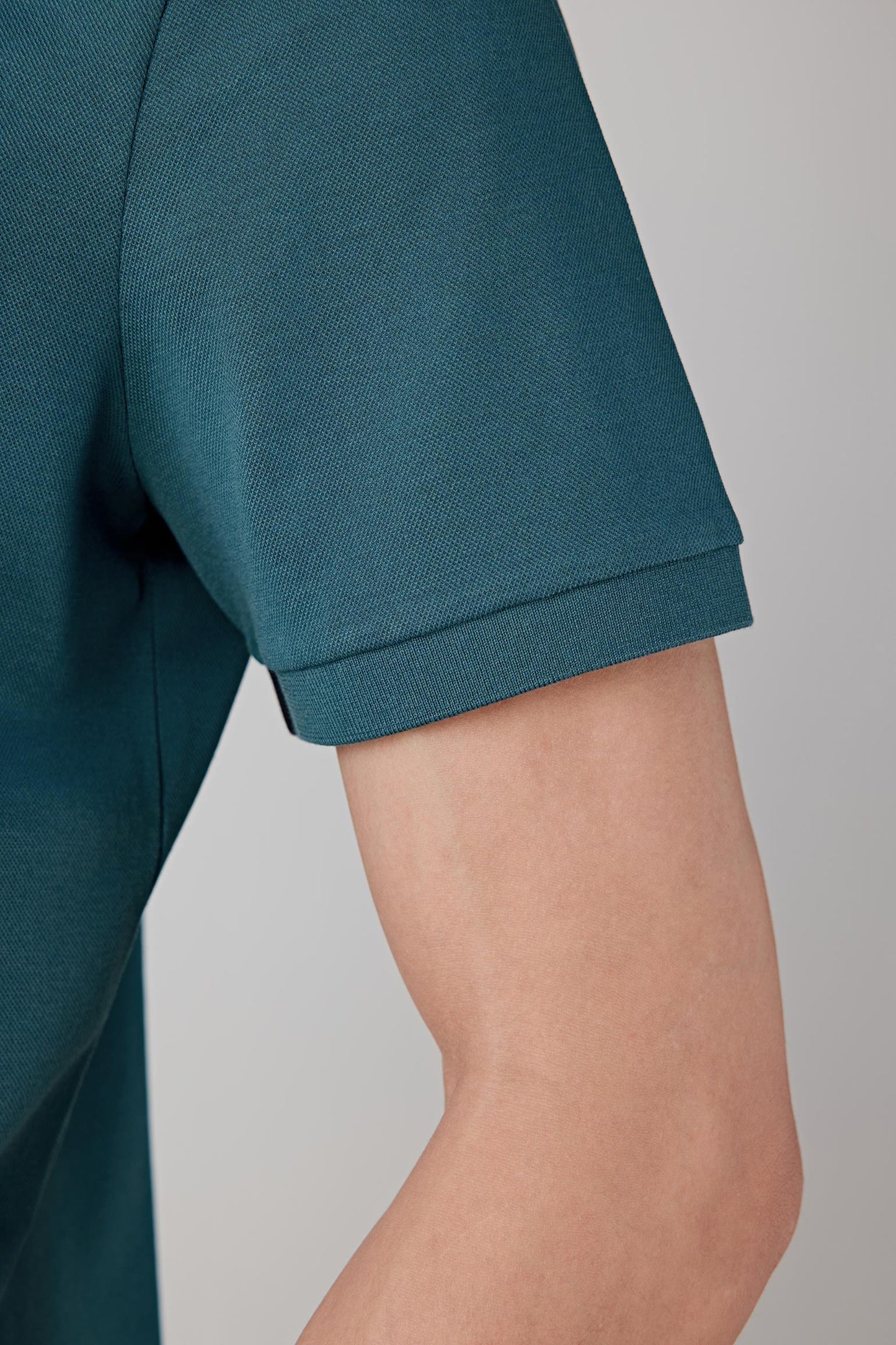 Close-up of the sleeve and side body highlighting the fabric texture, subtle structure and neat finishing at the sleeve edge.