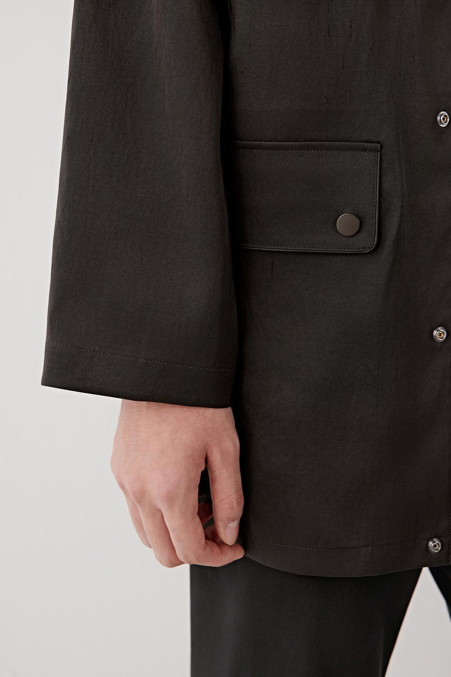 Detail of the lower front and sleeve, highlighting the soft fabric hand, minimal stitching and artisanal surface variations.