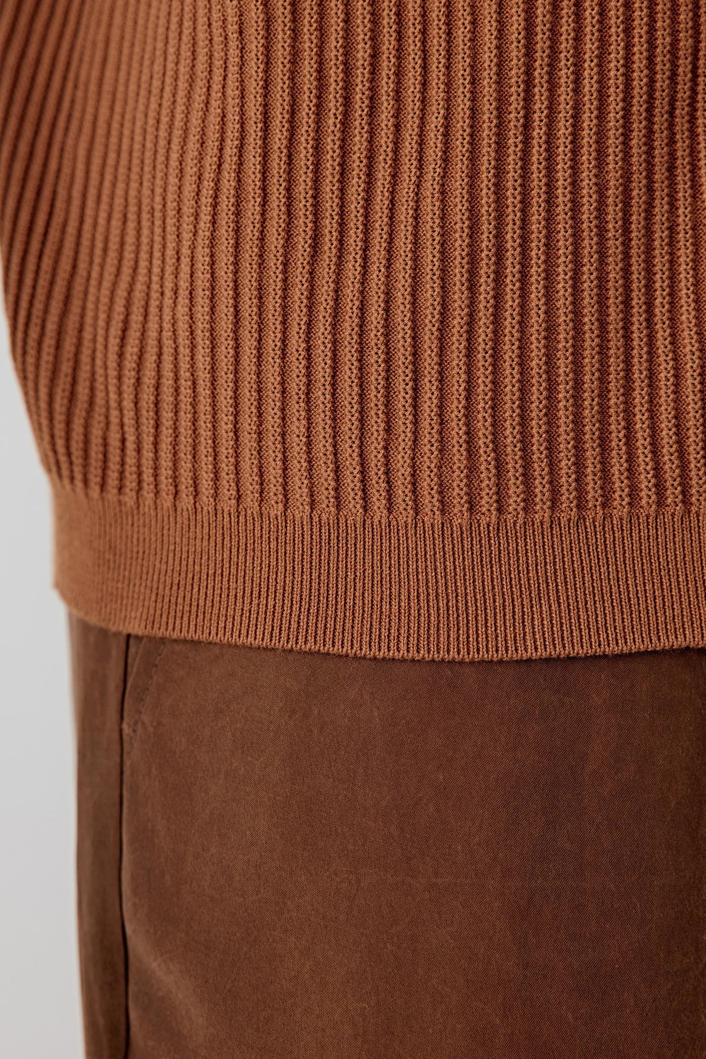 Close-up of the fabric and lower garment area, highlighting the vertical ribbing, elasticity of the knit and the soft, even surface with a dry hand feel typical of fine-spun cotton