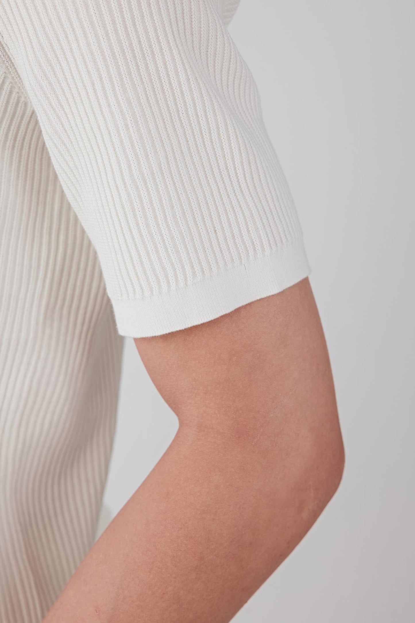 Close-up of the sleeve and upper arm, highlighting the short sleeve cut, clean finishing and the lightweight, breathable structure of the cotton knit