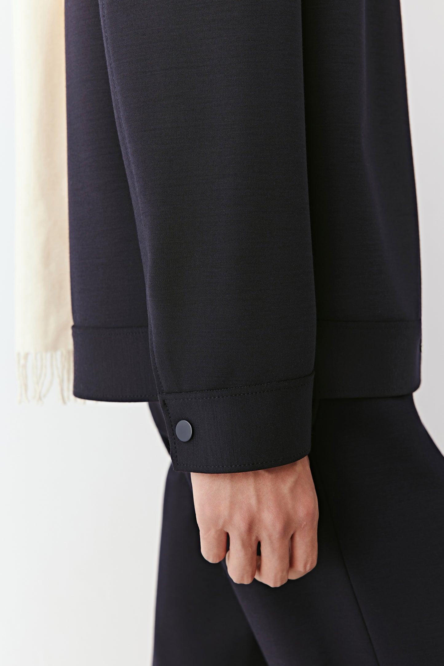 Detail of the hem and sleeve, focusing on the jacket’s smooth texture and refined craftsmanship.