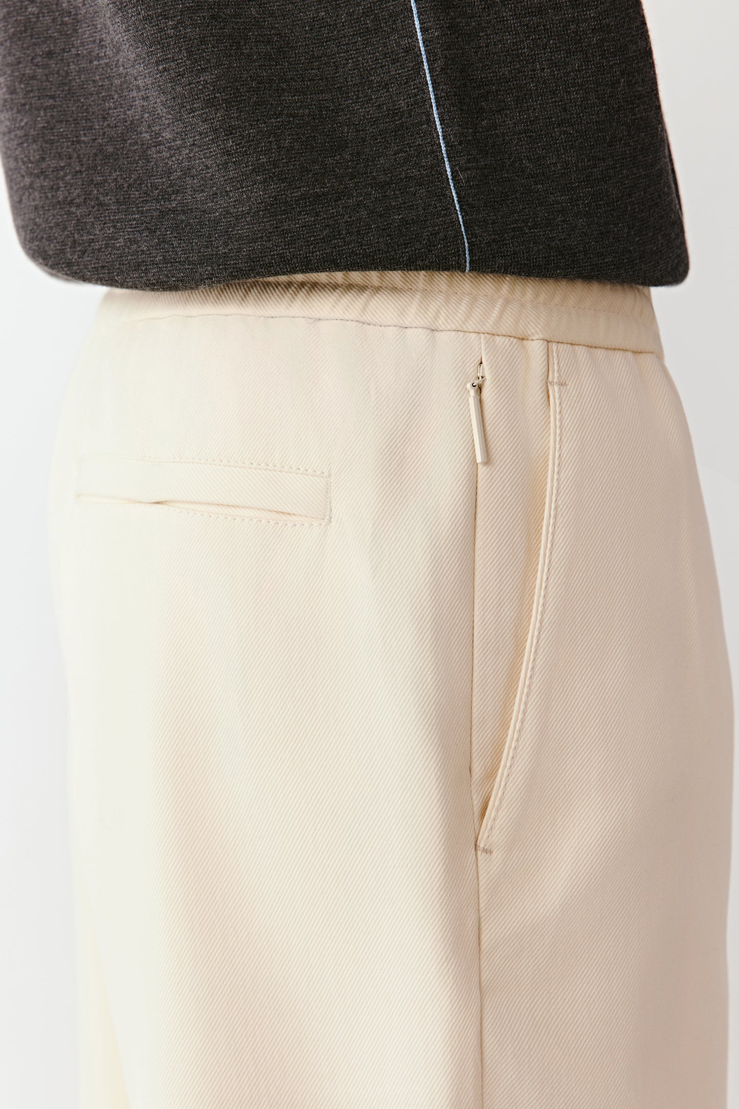 Beige pants with a black jacket on a white background