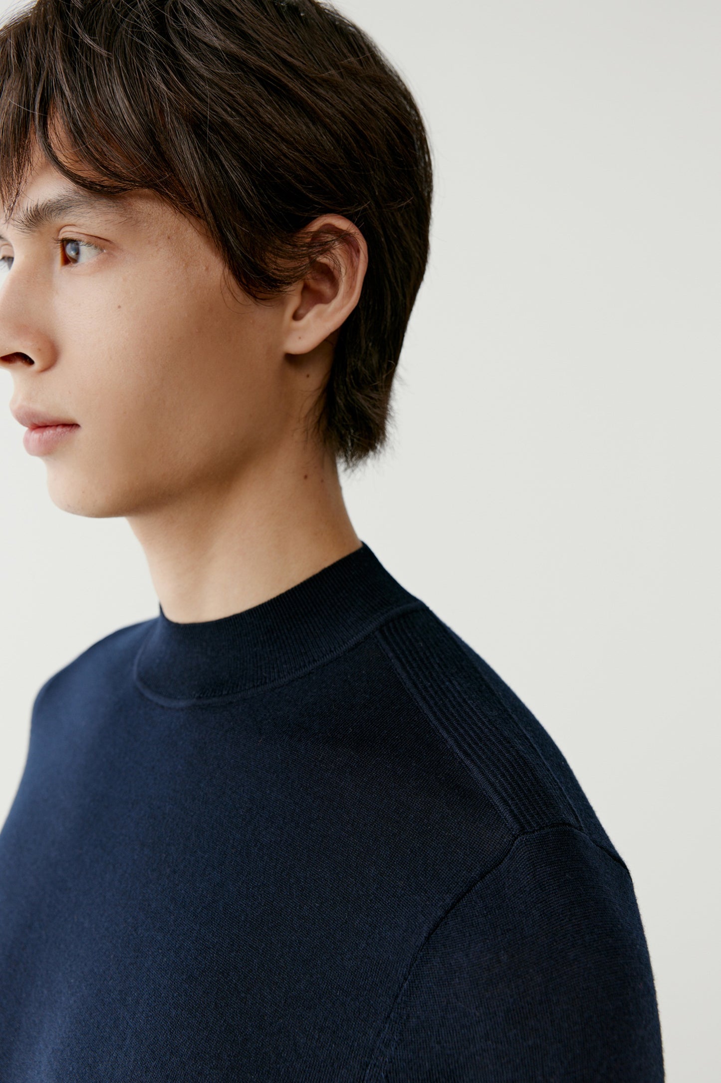 A portrait view focuses on the neckline and shoulder, revealing the smooth, compact texture of the fabric.