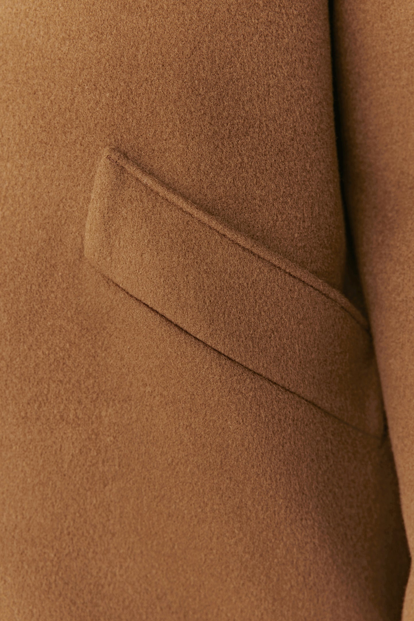 Detail shot of the camel merino wool fabric and pocket seam, showcasing the soft structure and quality craftsmanship.