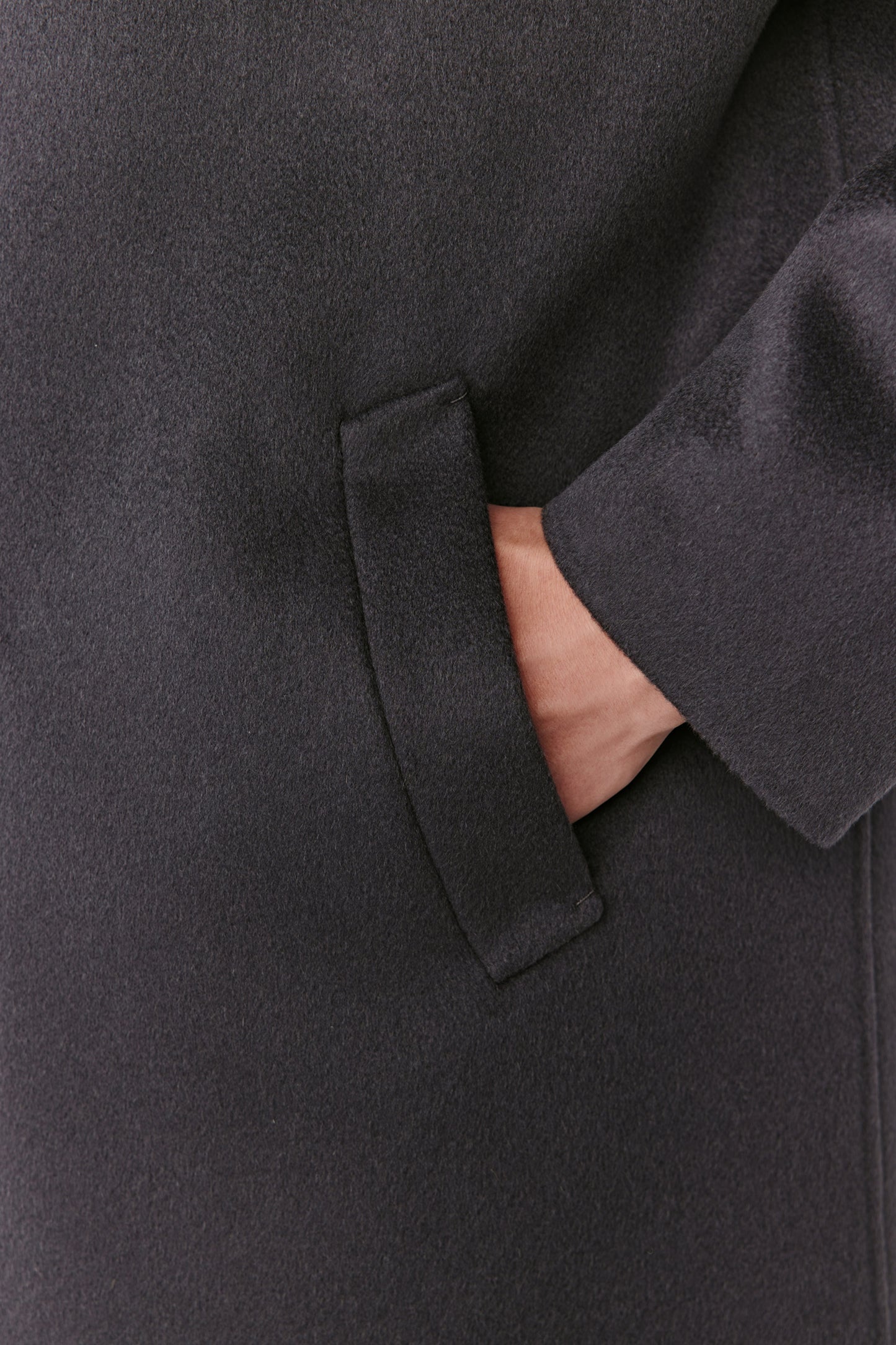 Close-up of a dark gray coat with a hand in the pocket