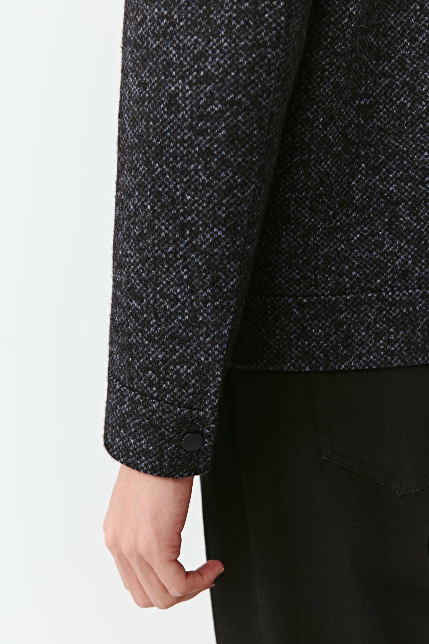 Close-up of a person wearing a dark gray textured sweater with a plain background