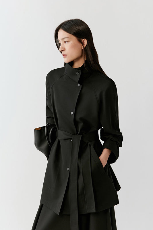 Three-quarter front view showing the coat’s drape, belt detail, and balanced proportions.