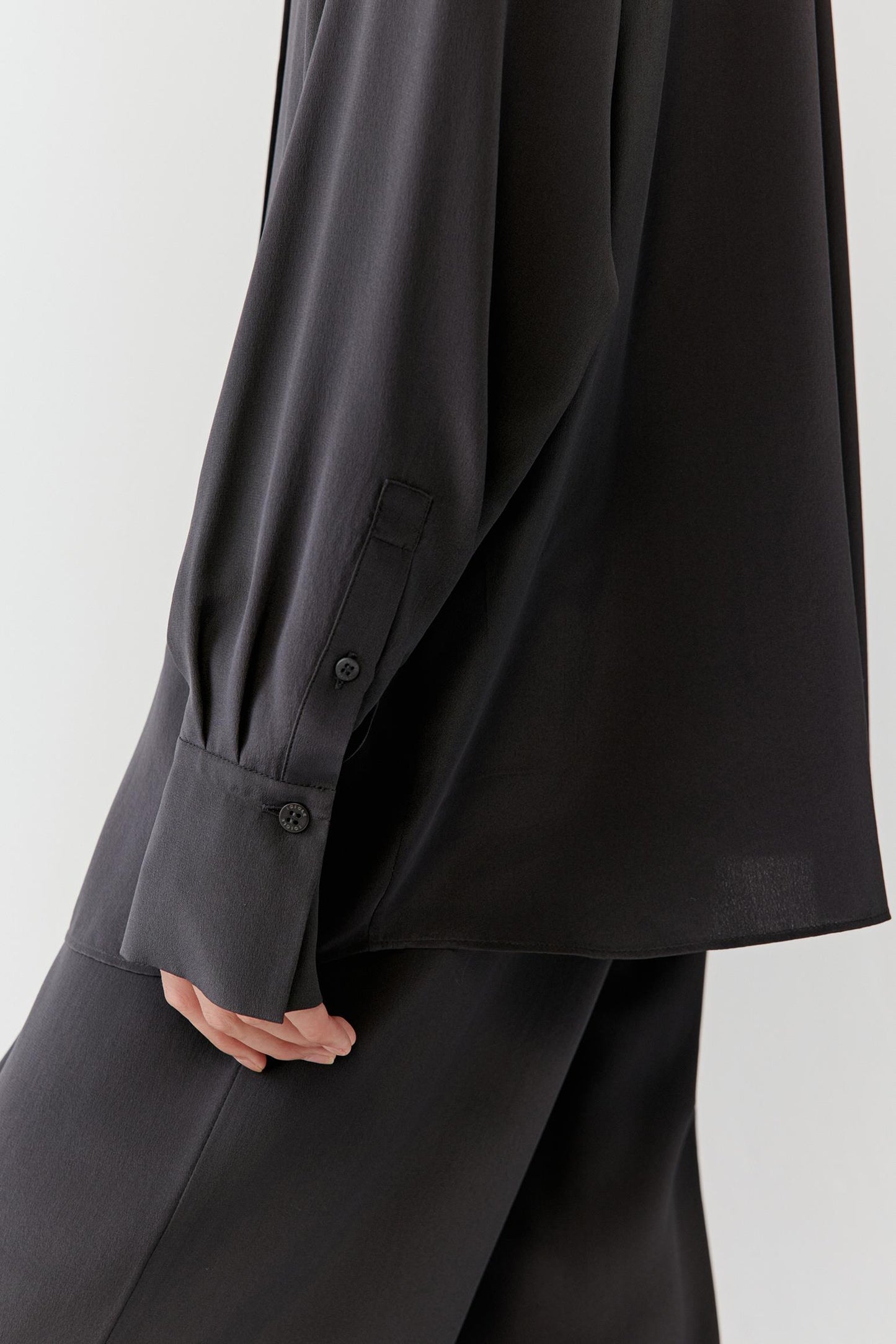 Detail of the cuff and sleeve, highlighting the soft movement of the fabric and buttoned cuff construction.