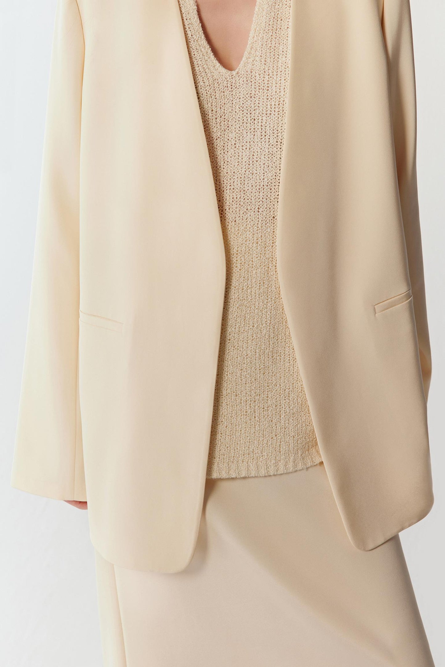 Close-up of the ivory silk crepe fabric and lapel, showing the fine texture, clean finishing and fluid structure.