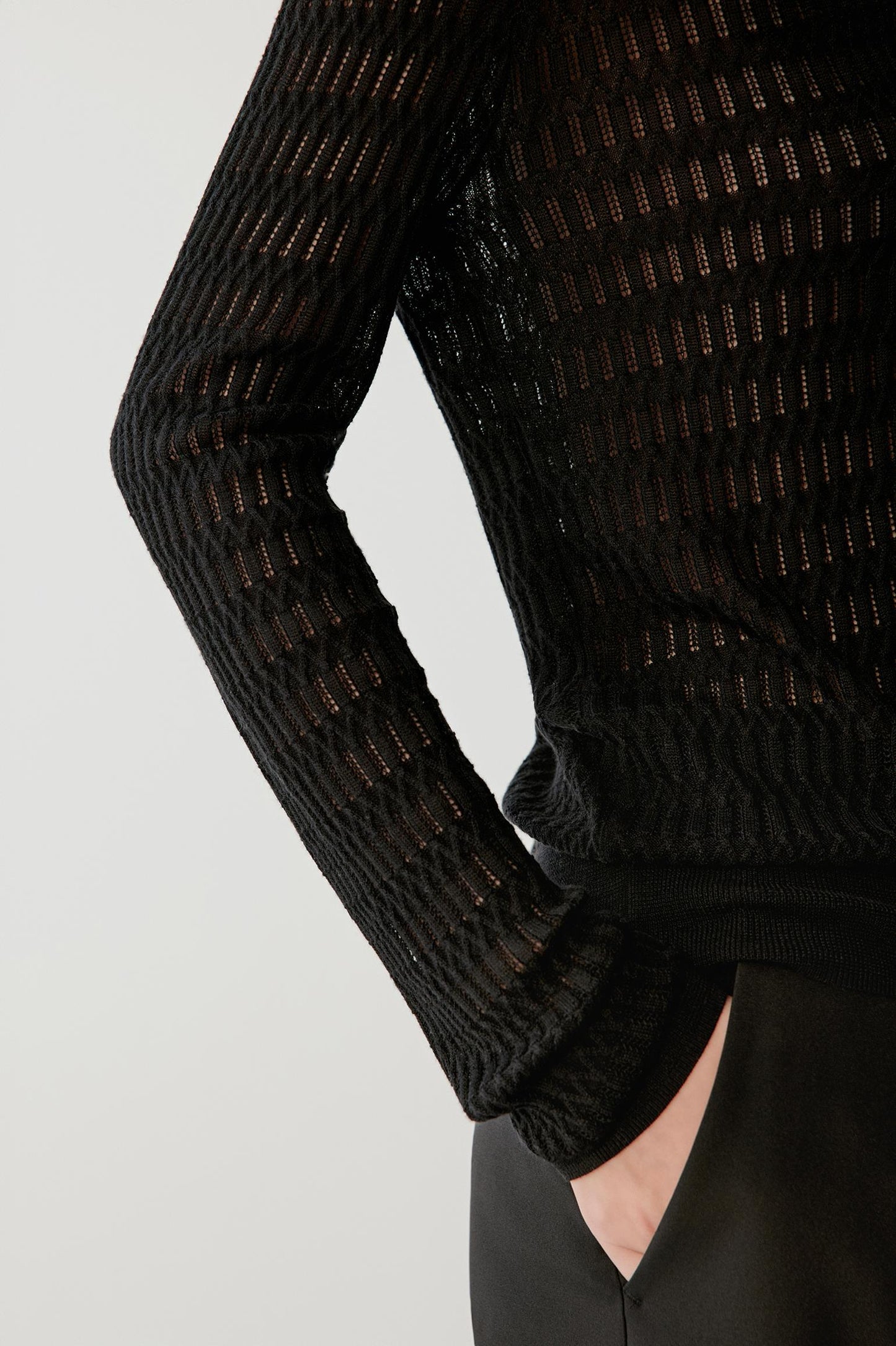 Detail of the knit fabric and sleeve, highlighting the lightweight openwork structure and soft, breathable texture.