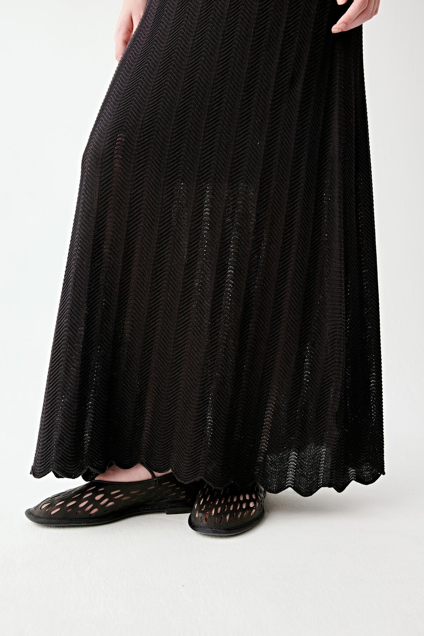 Close-up of the lower skirt and hem, highlighting the openwork knit structure, the airy movement of the fabric and the soft, fluid expansion of the flared hem