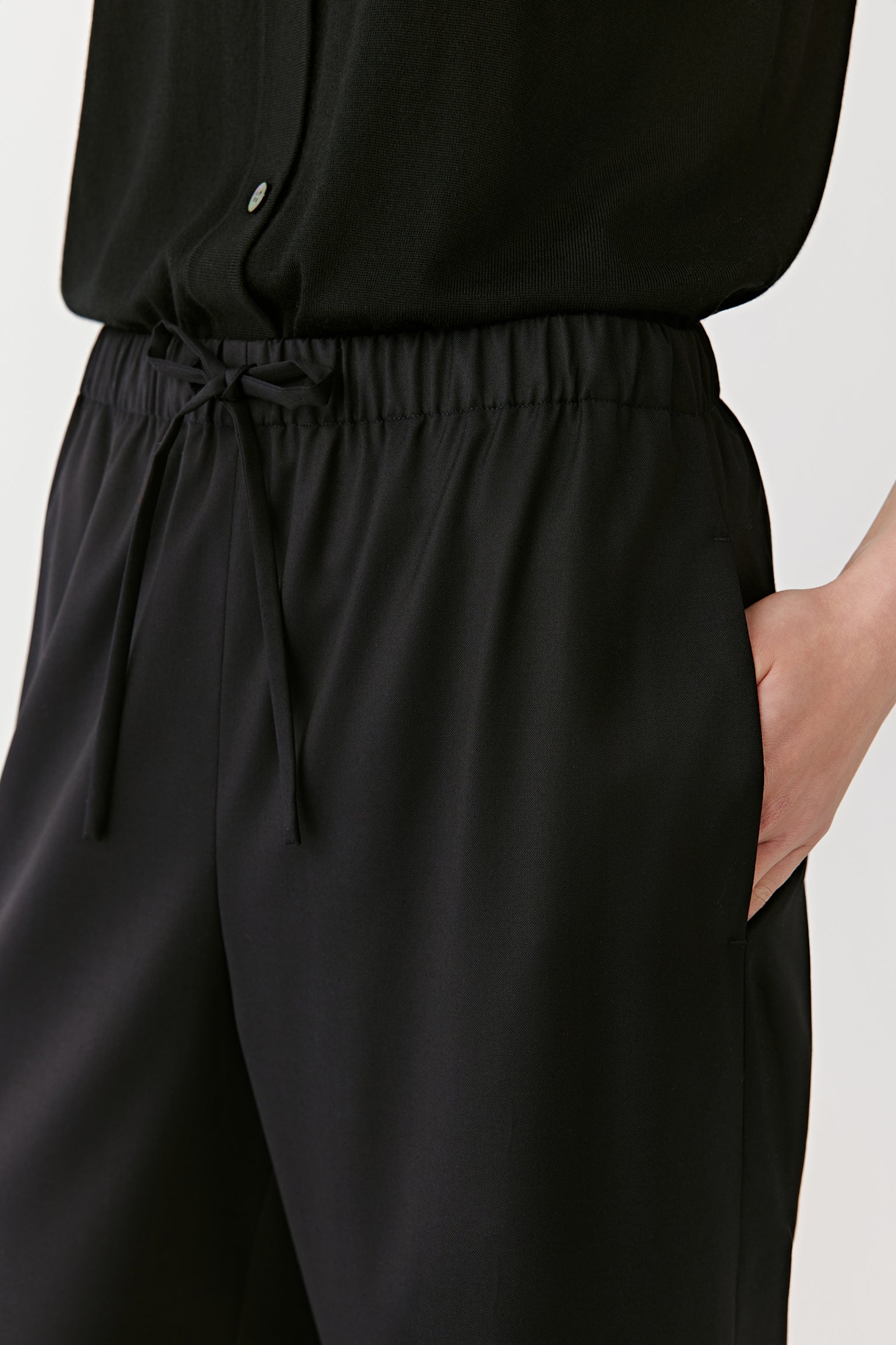 A close-up captures the waistband and drawstring detail, emphasizing comfort and fine tailoring.