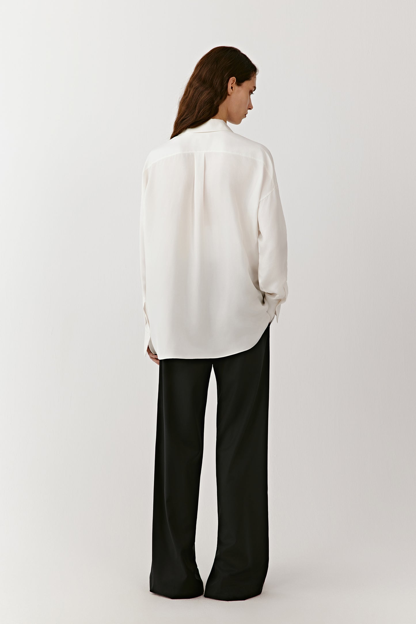 A view from behind highlights the long sleeves and relaxed silhouette of the shirt.