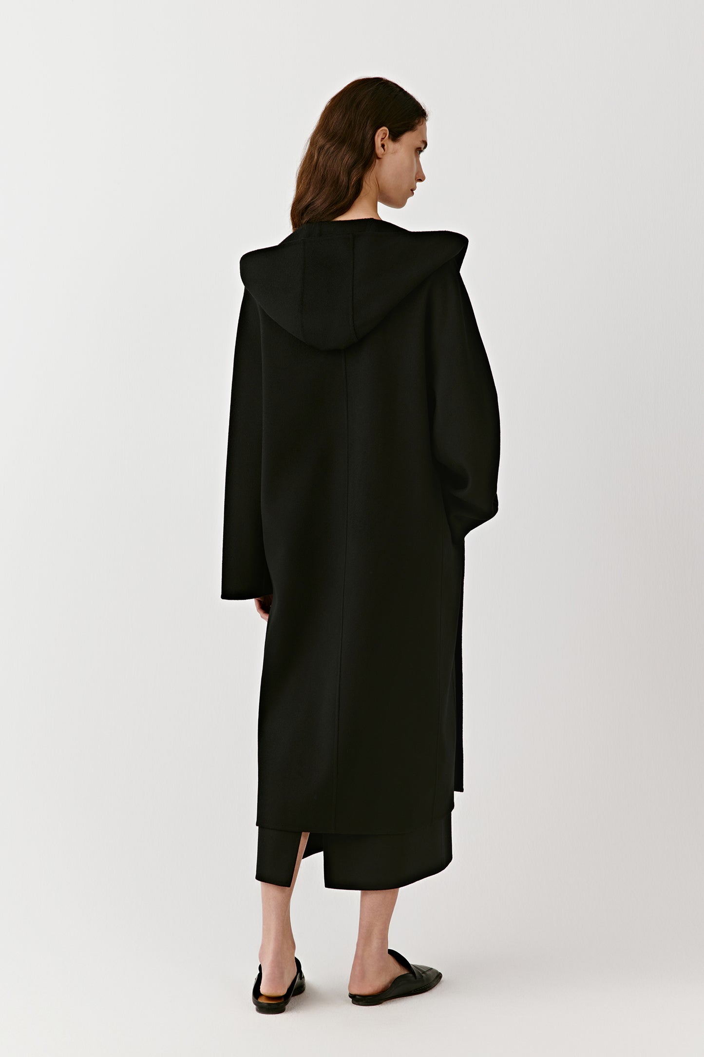 A side view captures the soft, enveloping volume and quiet movement of the coat.
