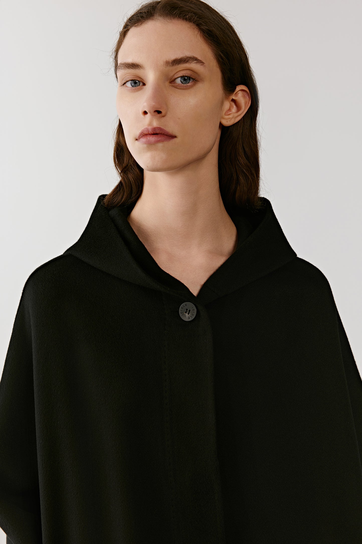 A portrait highlights the face framed by the hood, with light falling softly across the surface.