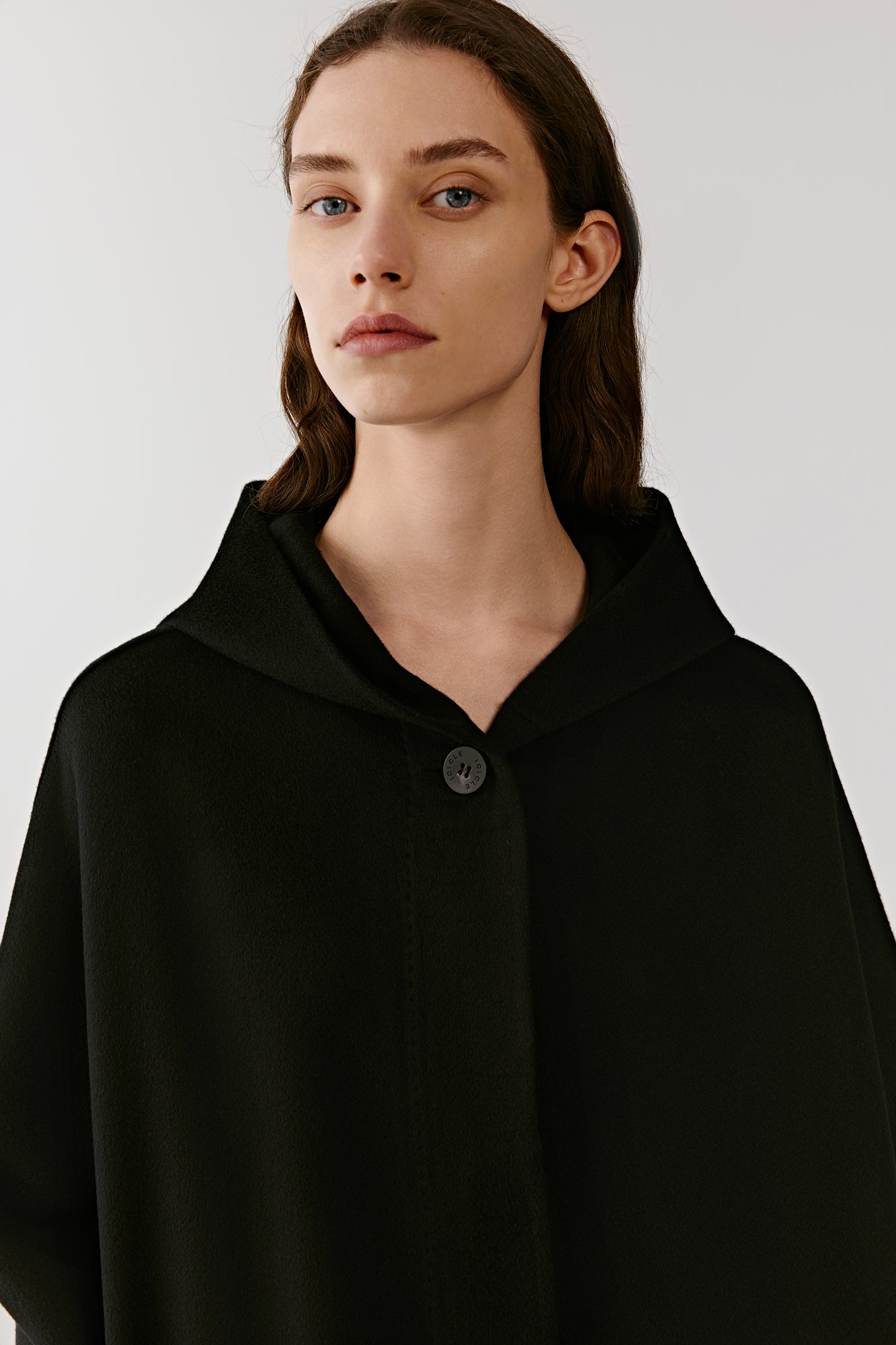 A portrait highlights the face framed by the hood, with light falling softly across the surface.