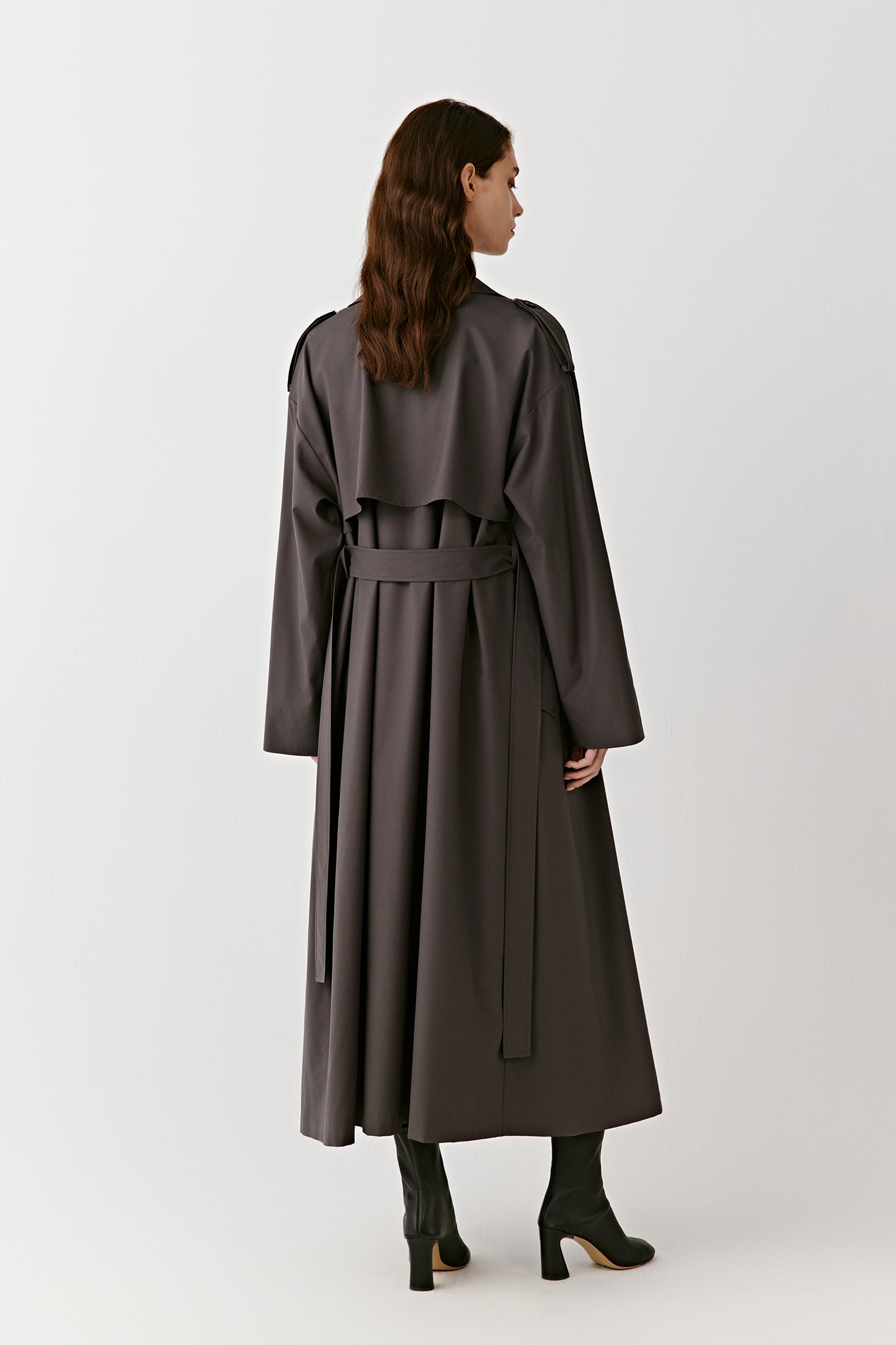 A full-length frame shows the coat’s elongated line and fluid silhouette in motion.