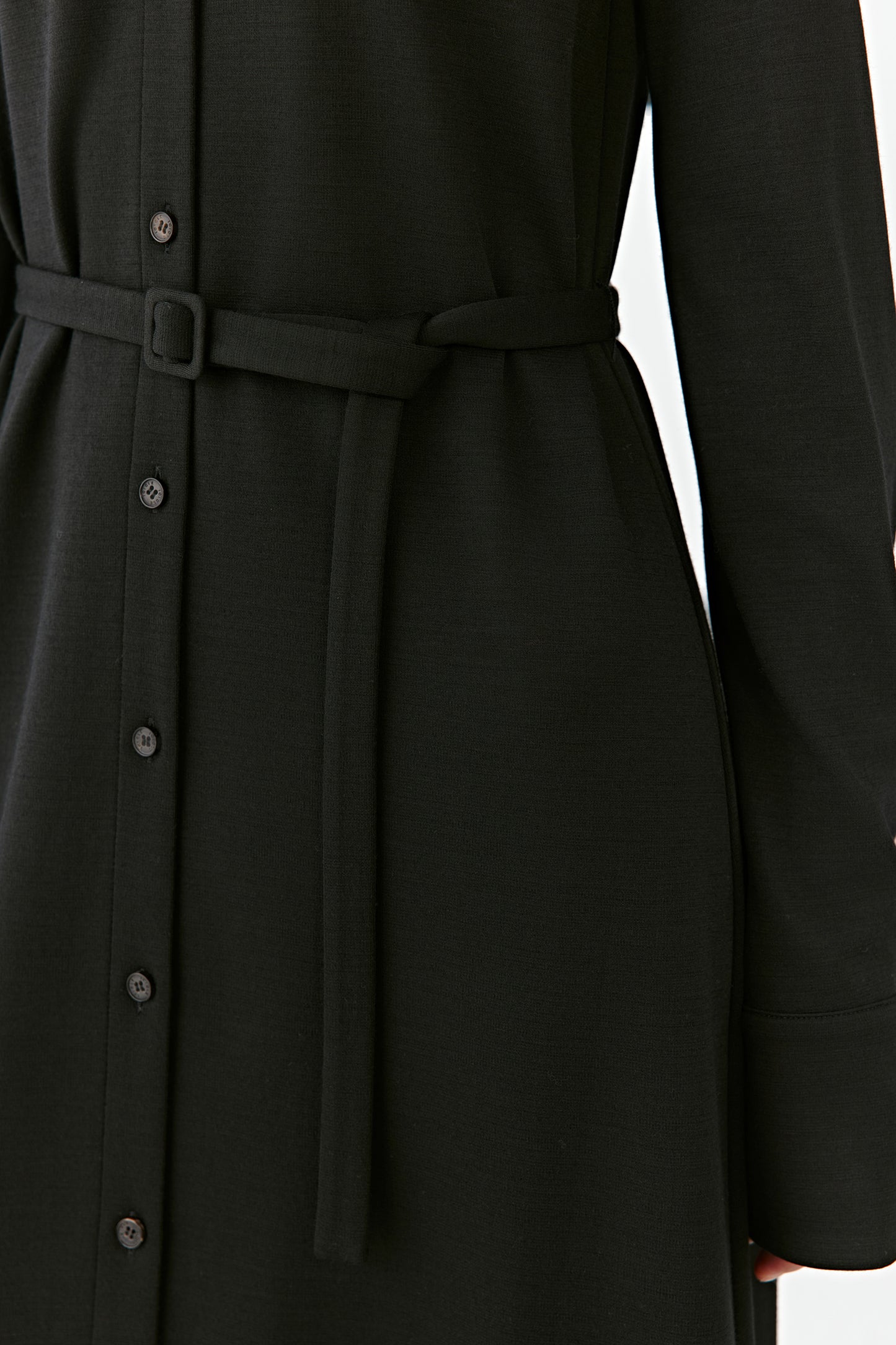 A detailed shot reveals the button placket and the subtle structure of the belt.