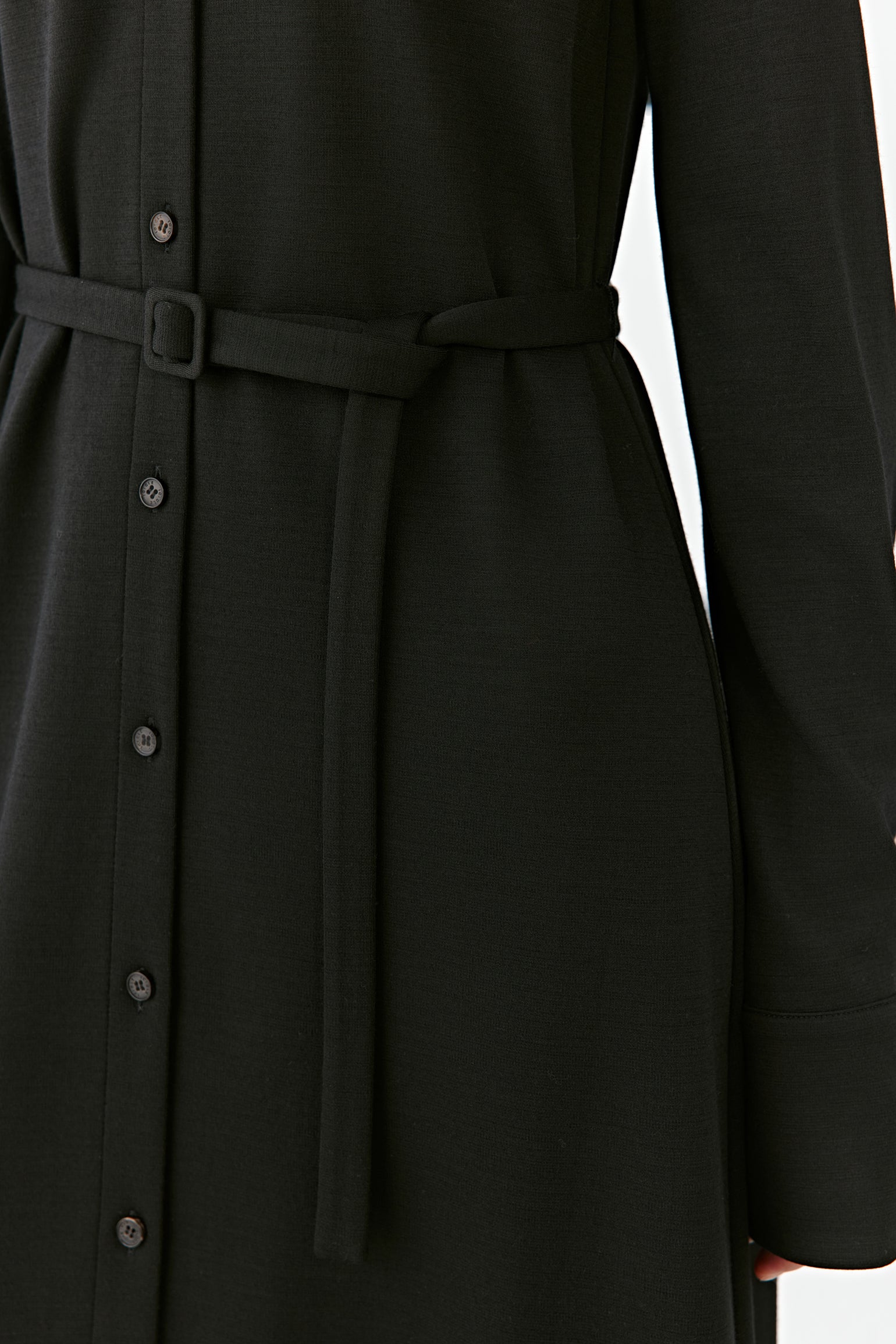 A detailed shot reveals the button placket and the subtle structure of the belt.