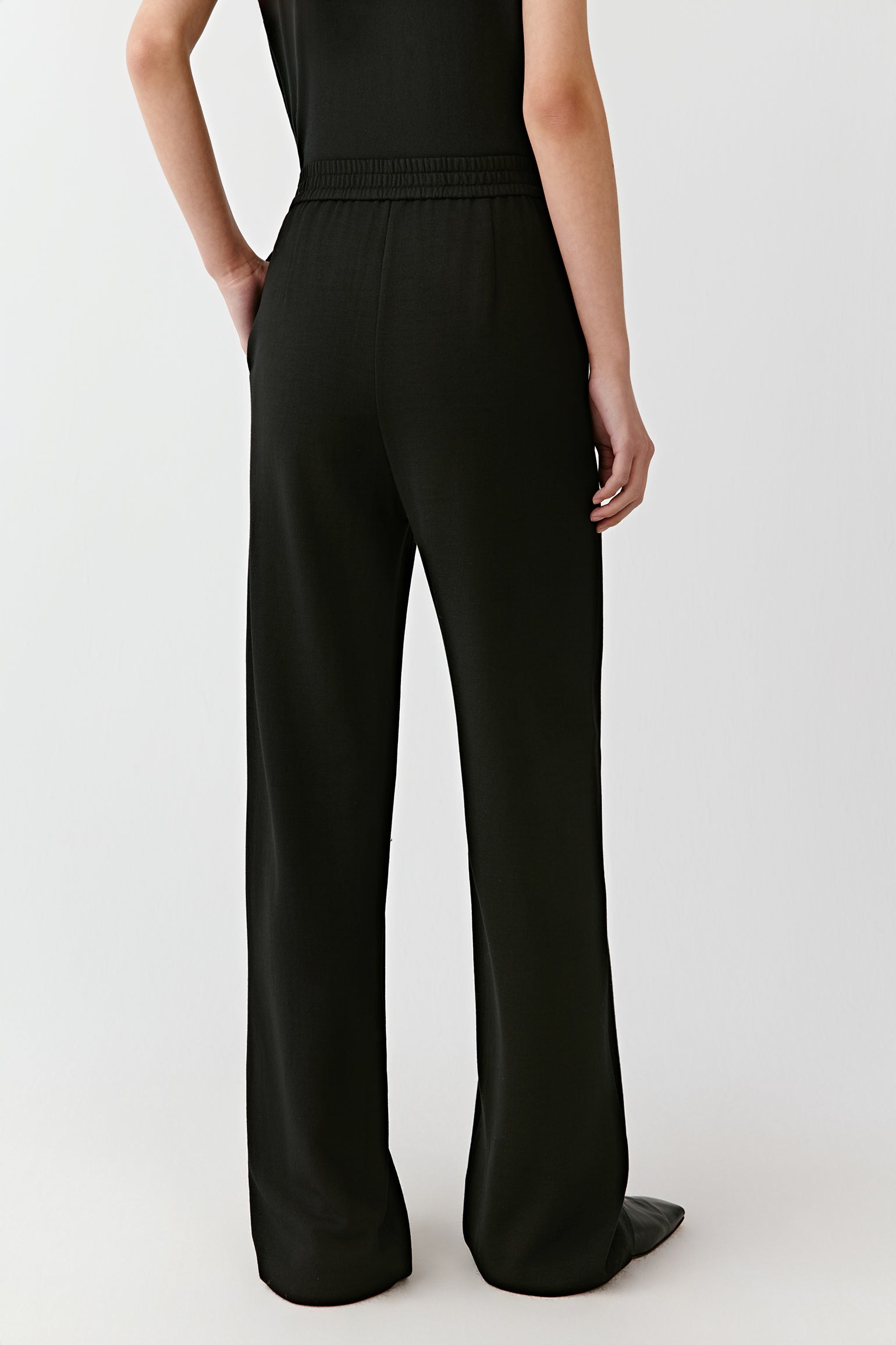 A back shot captures the soft fall of the trousers and the light texture of the wool.