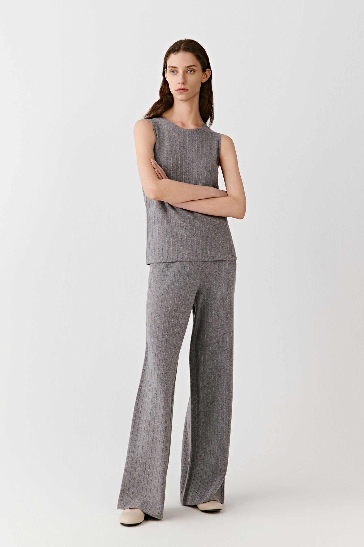 Model wearing a sleeveless gray ribbed knit top with matching wide-leg pants, minimalist look against a plain background.
