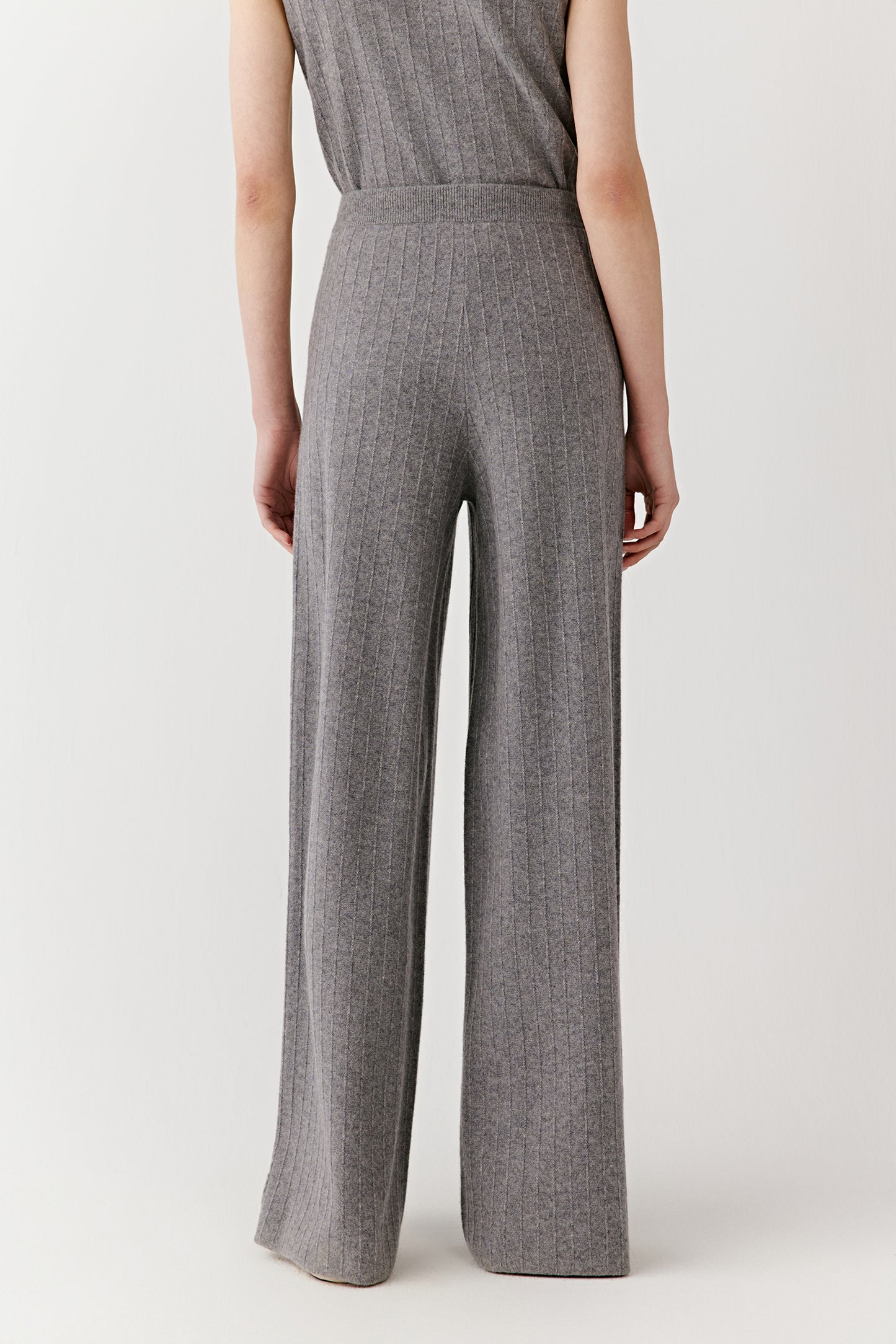 Profile view showing the drape and movement of the gray ribbed knit pants.