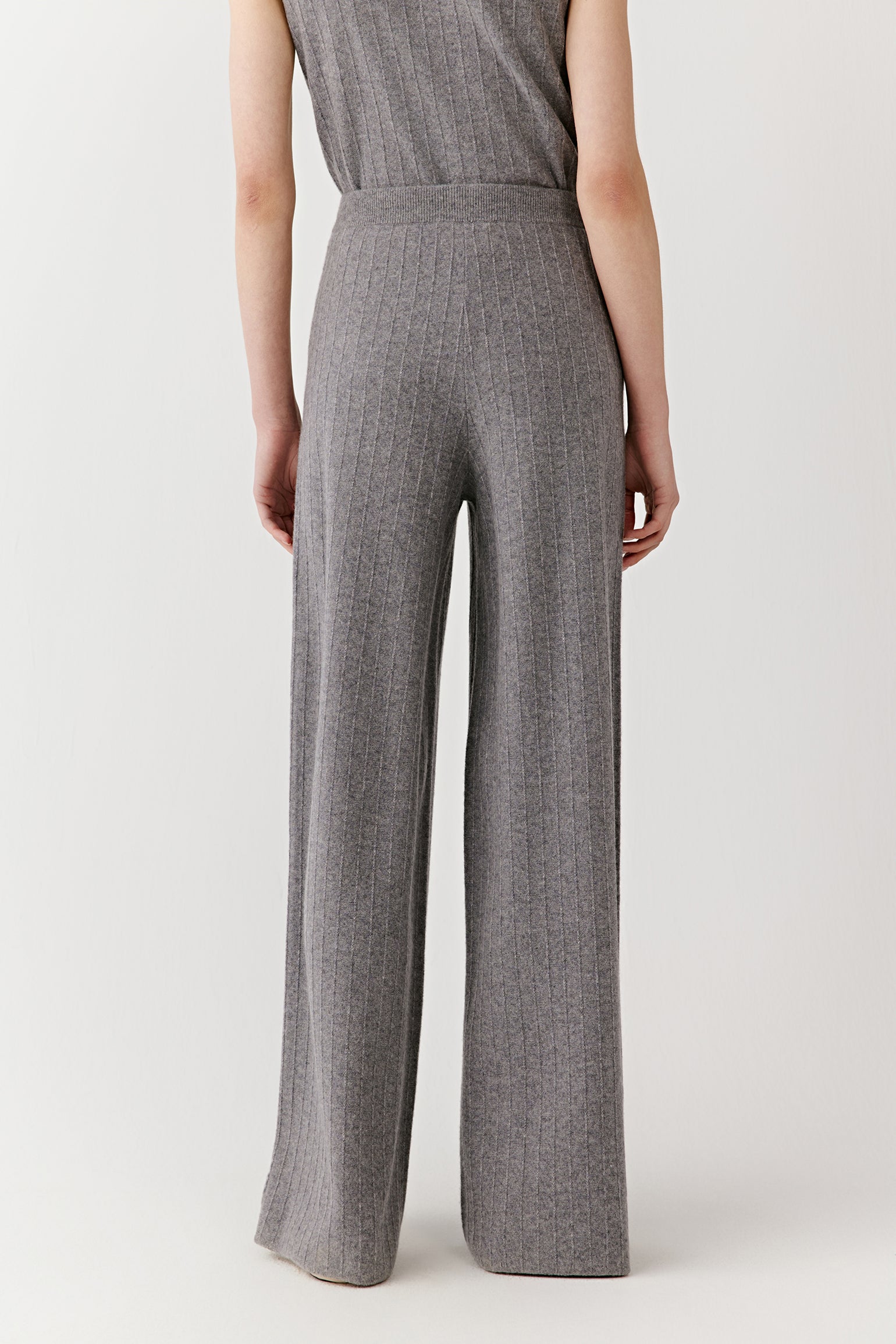 Profile view showing the drape and movement of the gray ribbed knit pants.