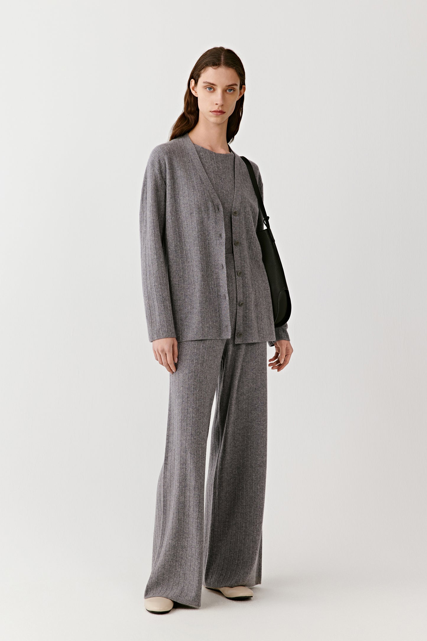 Model wearing a gray ribbed knit cardigan with matching wide-leg pants and neutral shoes, minimalist styling.