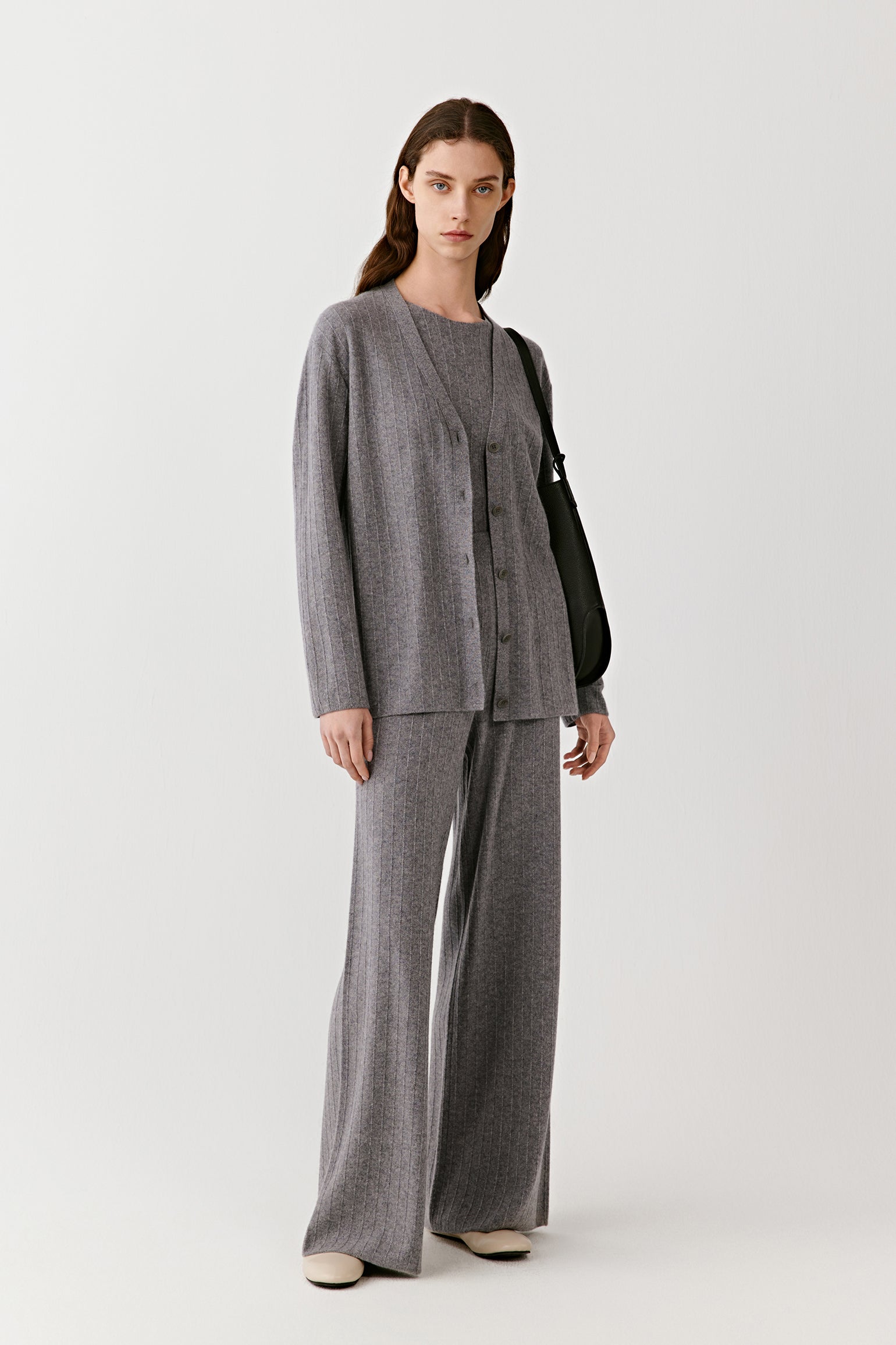 Model wearing a gray ribbed knit cardigan with matching wide-leg pants and neutral shoes, minimalist styling.