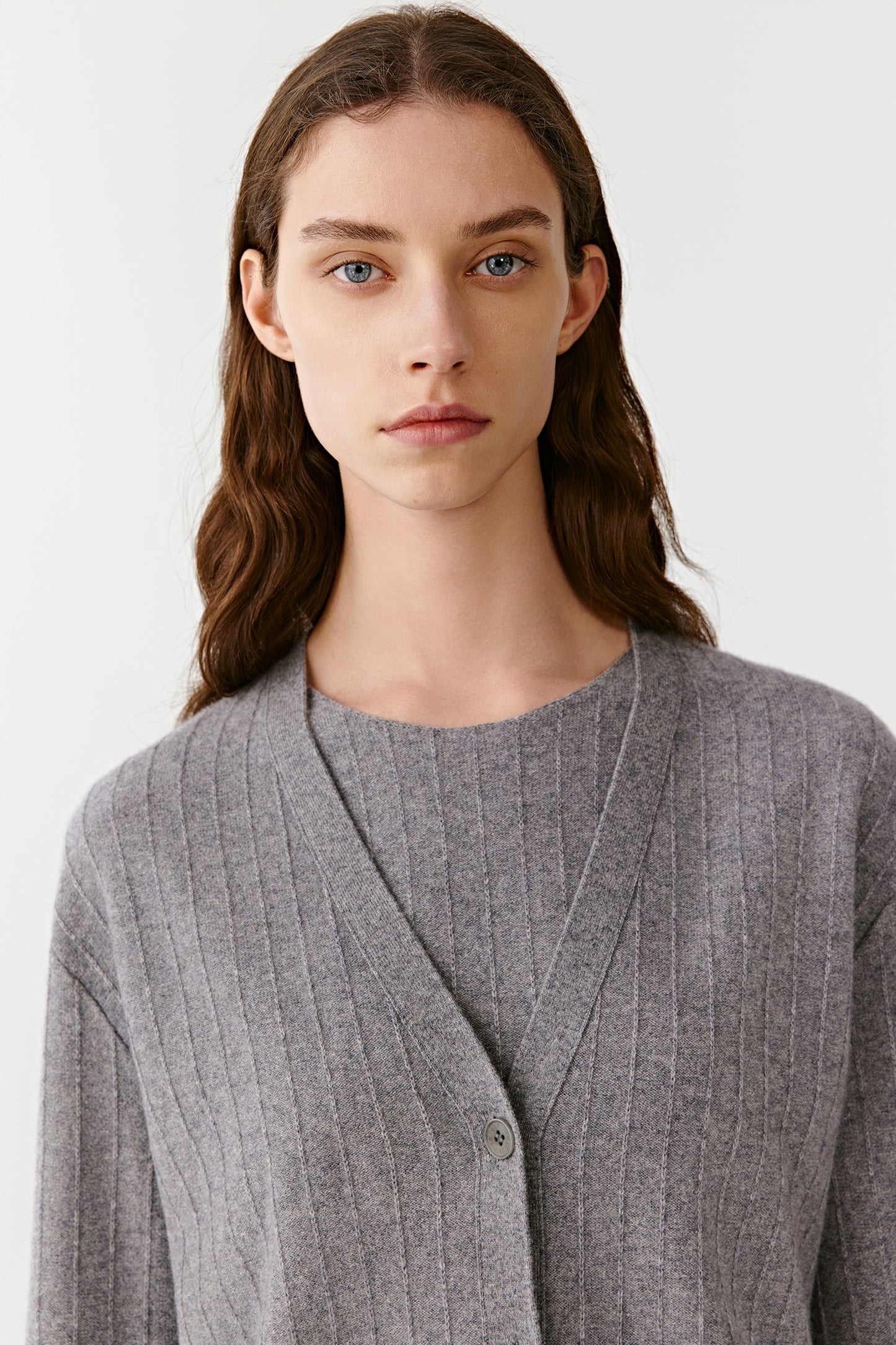 Model facing slightly sideways, showing button-up front and loose fit of the gray ribbed cardigan.
