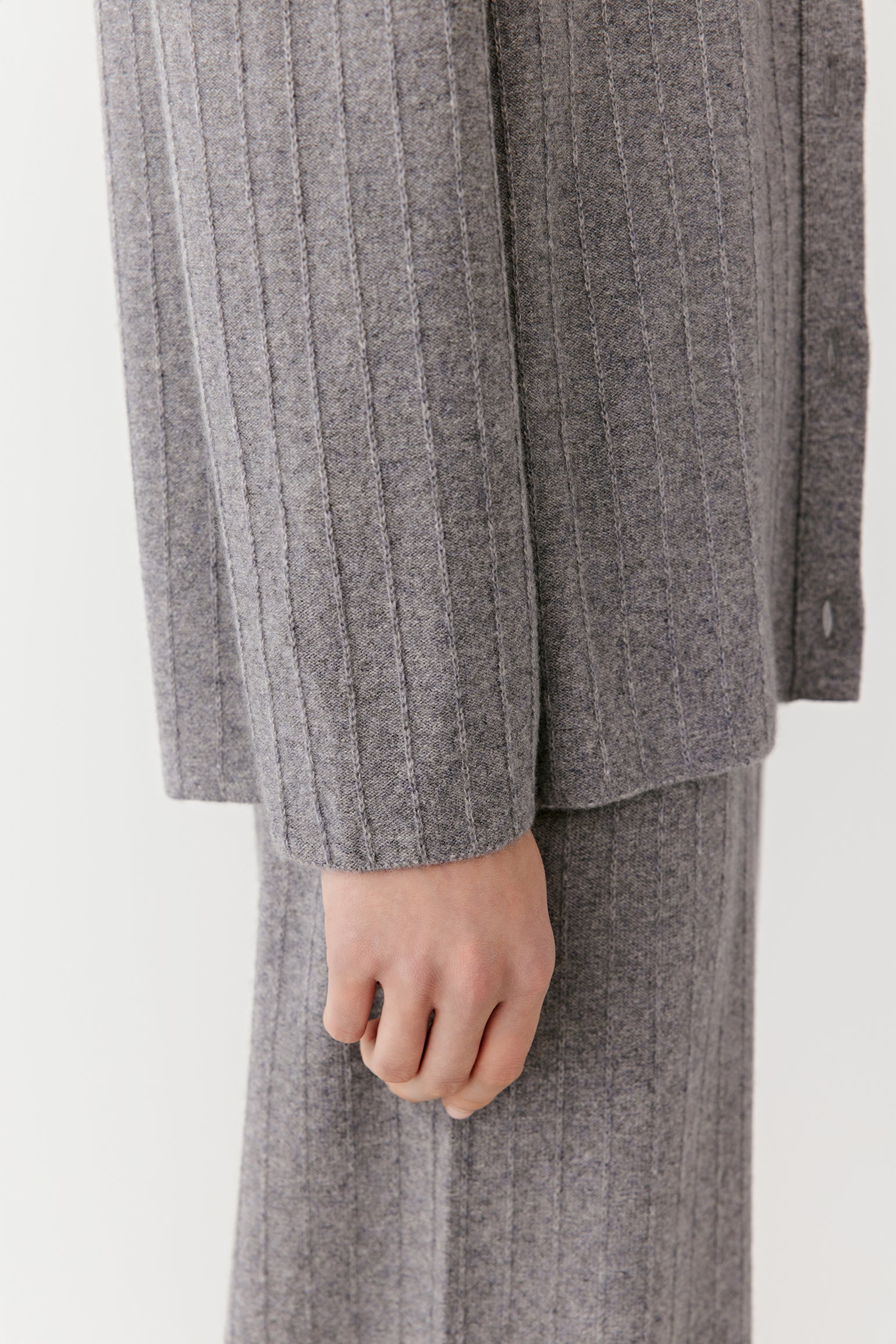 Close-up of the gray ribbed knit cardigan, focusing on the sleeve hem and fine knit texture.