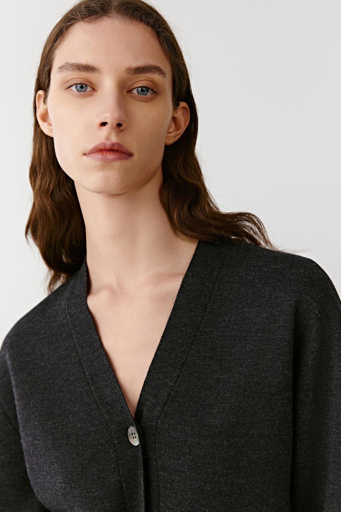 Close-up of the deep V neckline and smooth knit texture of the black cashmere cardigan.