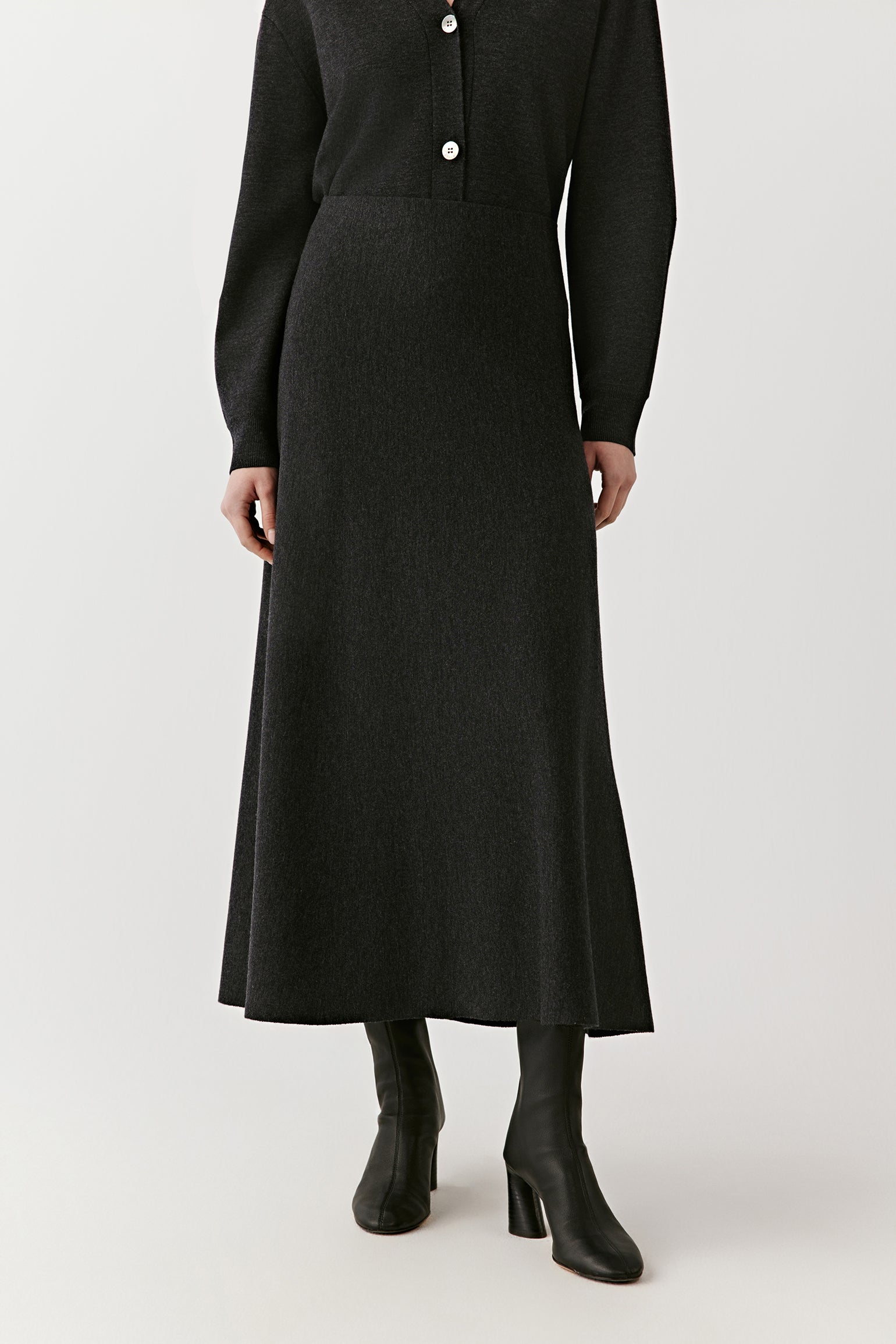 Back view of a long black knit skirt with button front design on a light background