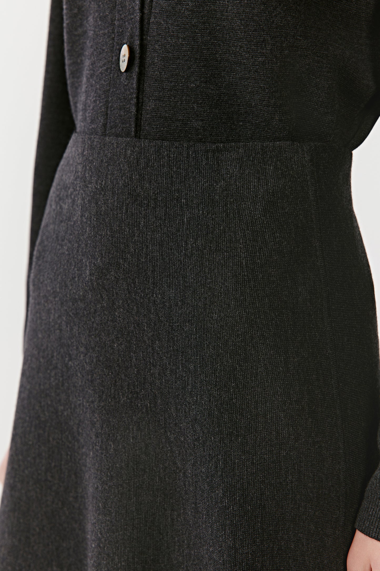 Detail of a long black knit skirt fabric and fit on a light background
