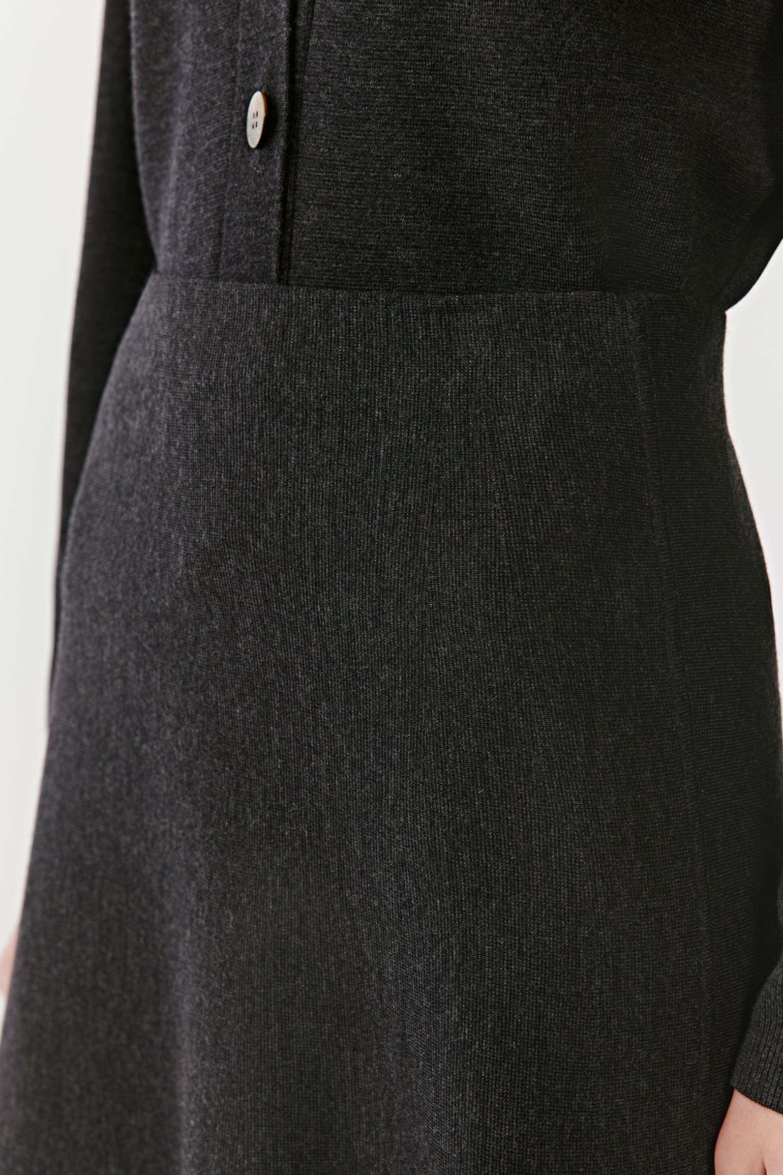 Detail of a long black knit skirt fabric and fit on a light background