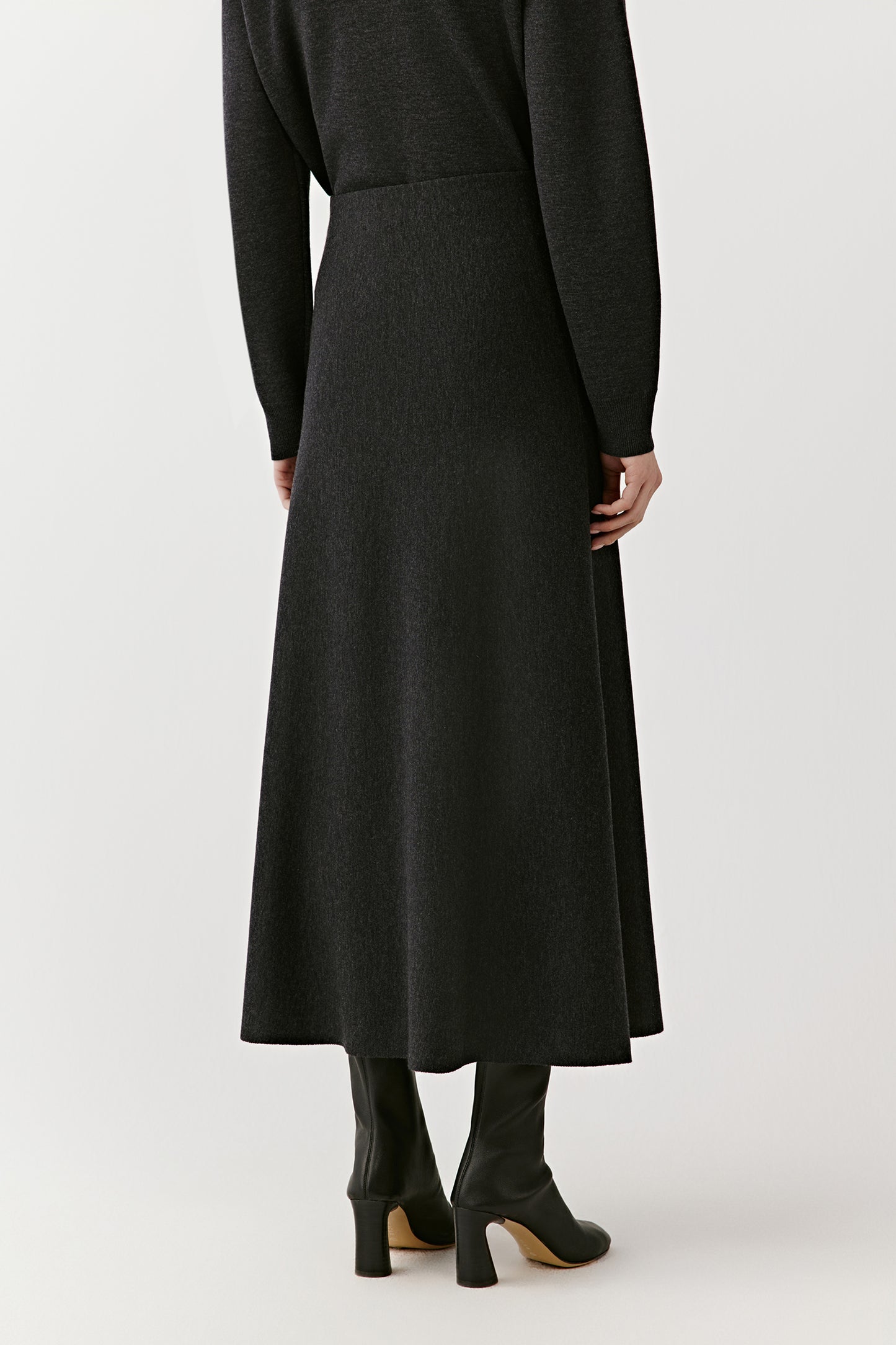 Close-up of a black knit skirt buttons and ribbed texture on a light background