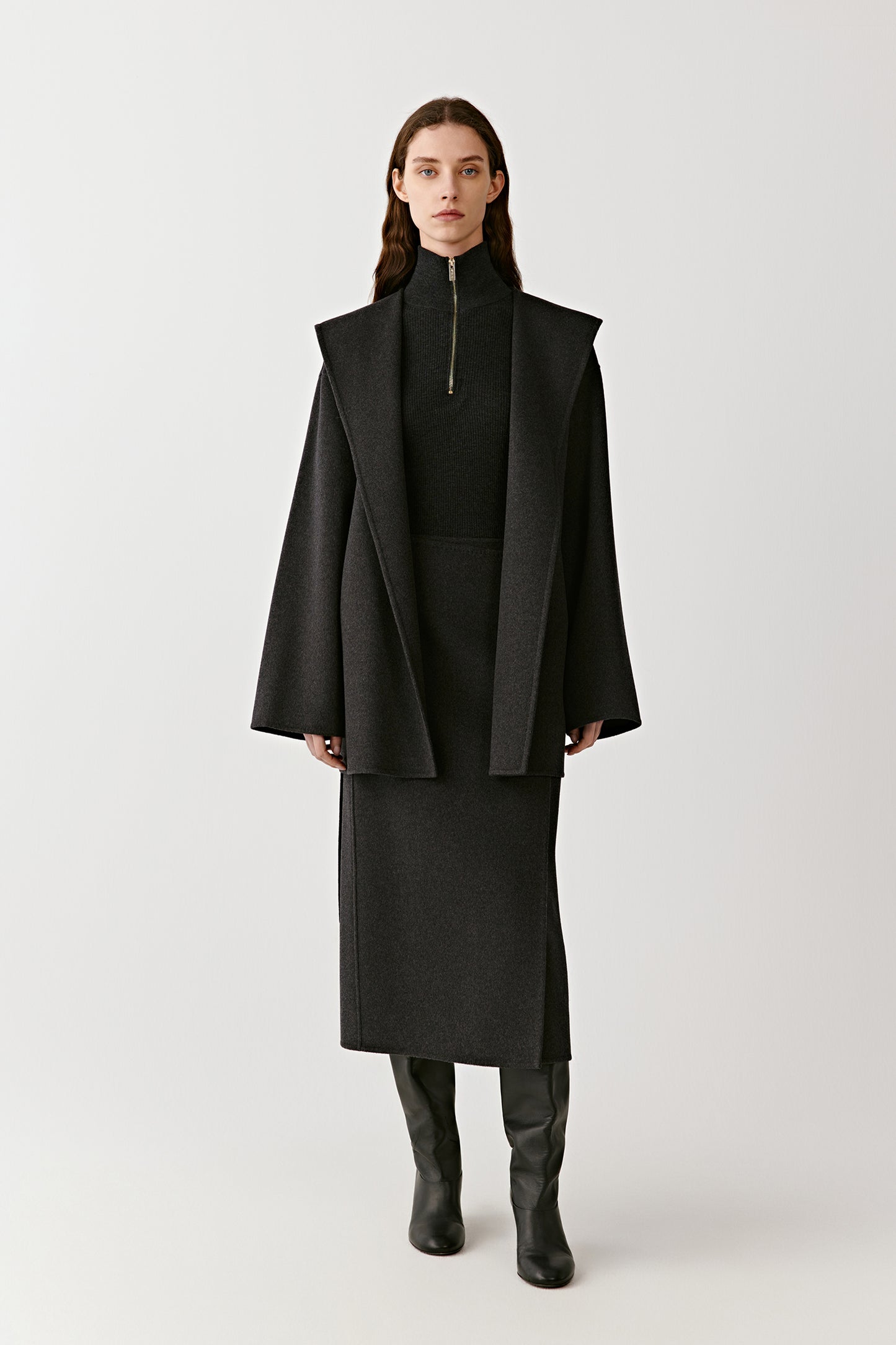 Full body view of a long black hooded wool coat with tie belt on a light background
