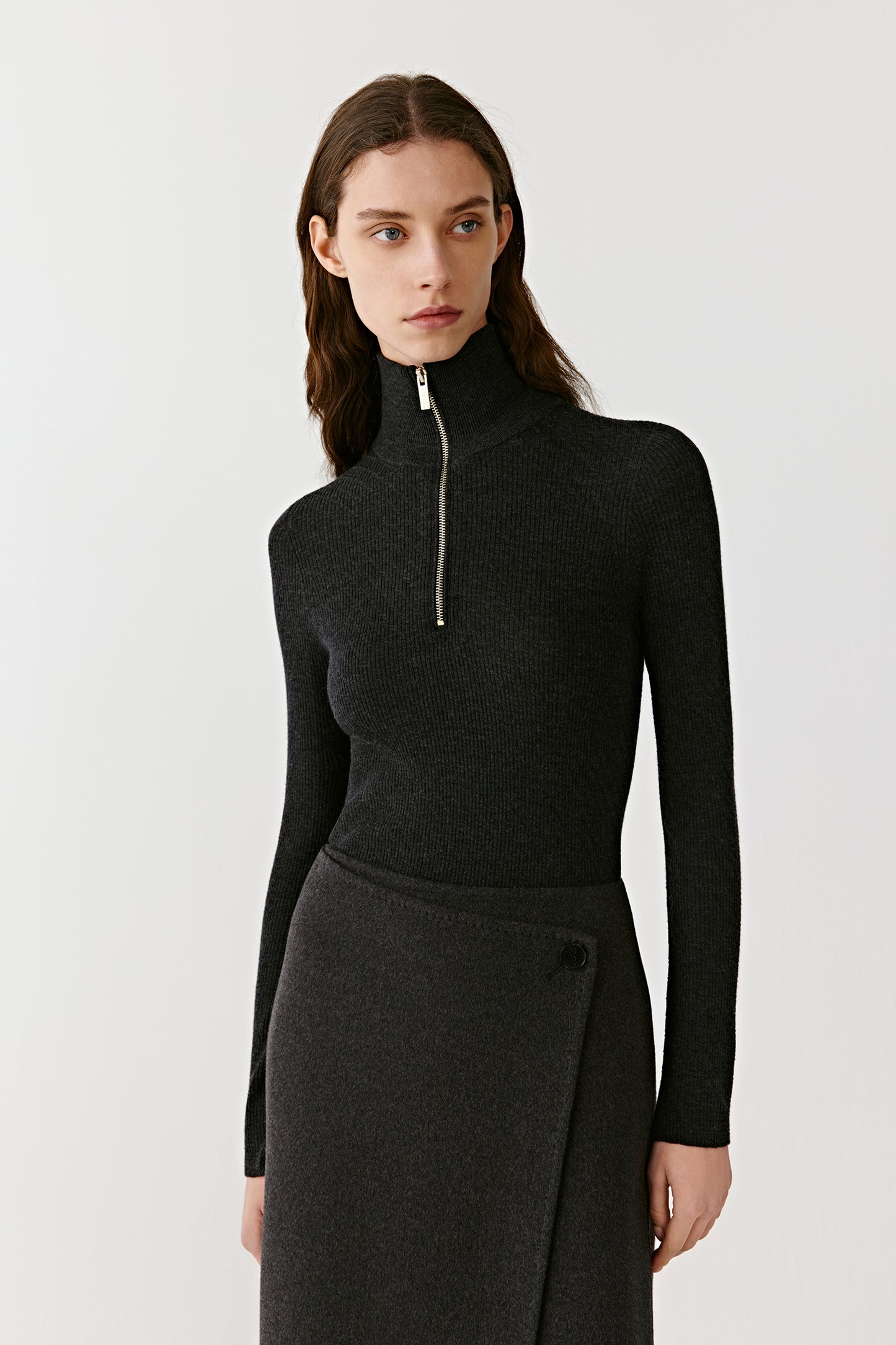 Front view of a woman wearing a fitted black cashmere jumper with high zip neck and long sleeves.