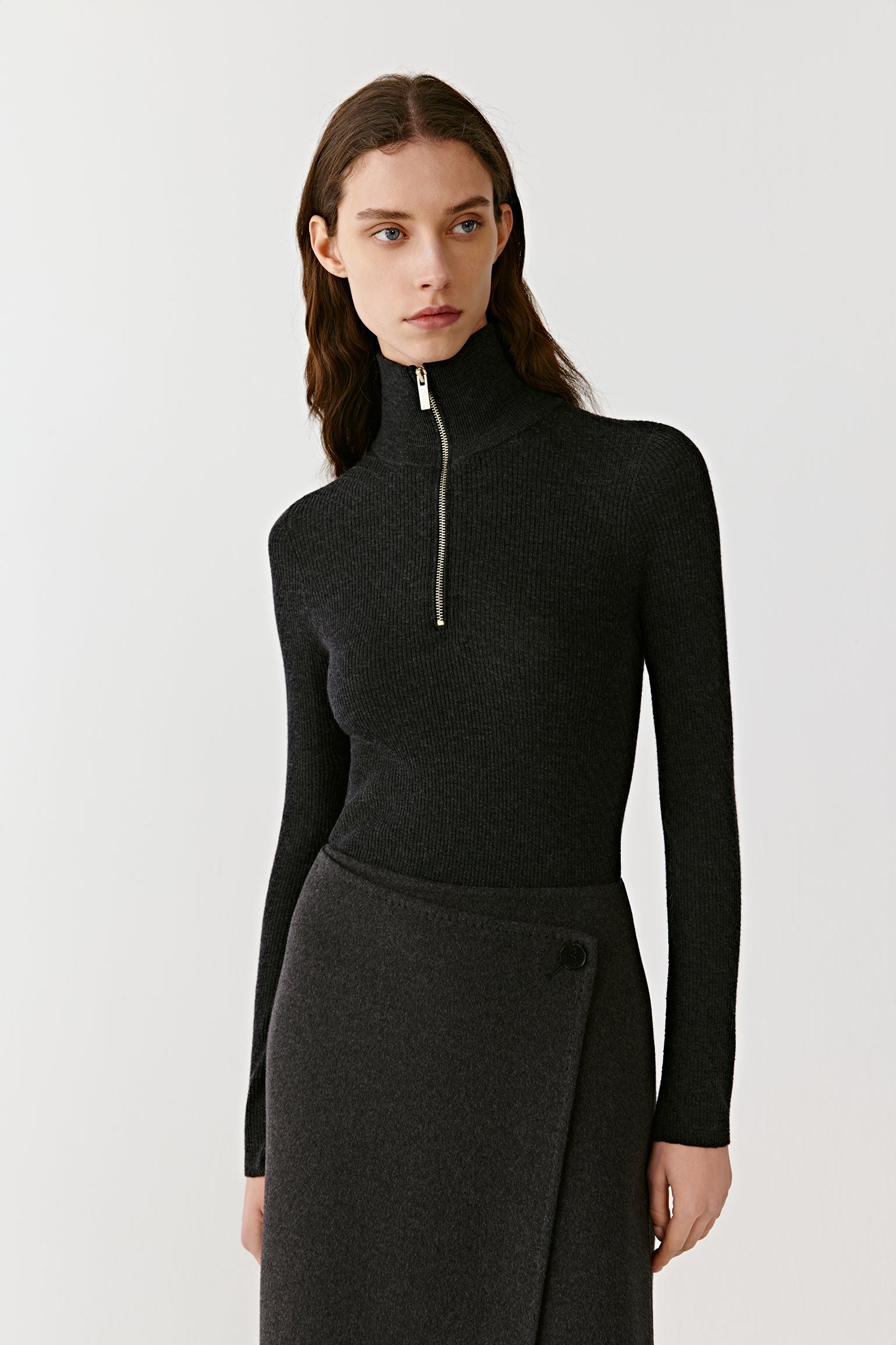 Front view of a woman wearing a fitted black cashmere jumper with high zip neck and long sleeves.