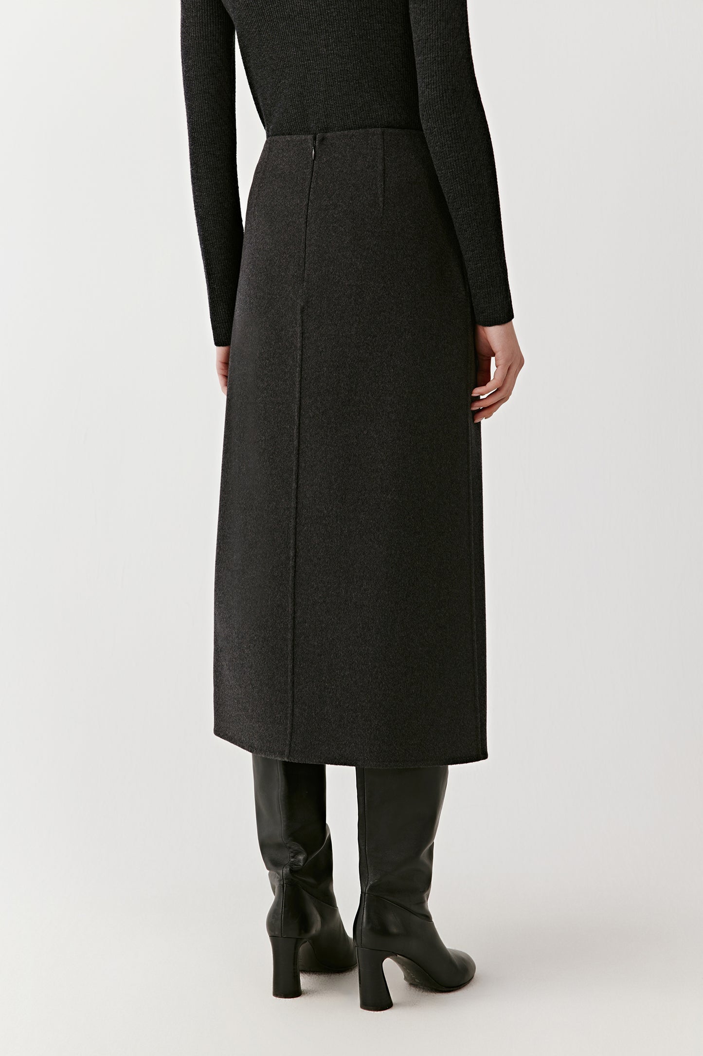 Rear view of the dark grey wrap skirt paired with a dark grey turtleneck, showing the straight silhouette and smooth drape.