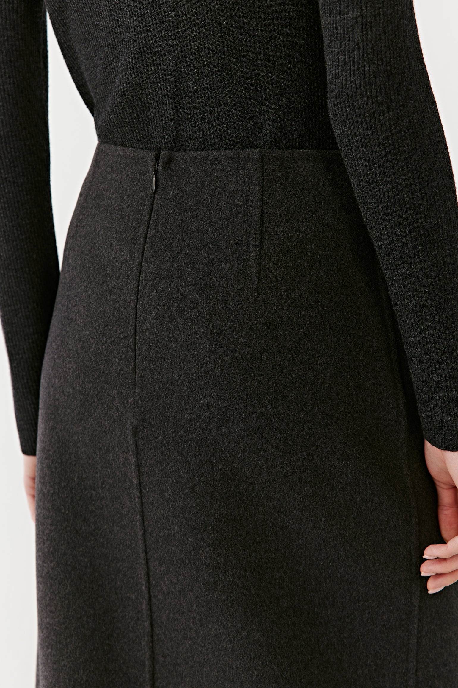 Close-up of the side seam and wrap overlap of the dark grey skirt, highlighting tailoring details and fine wool texture.