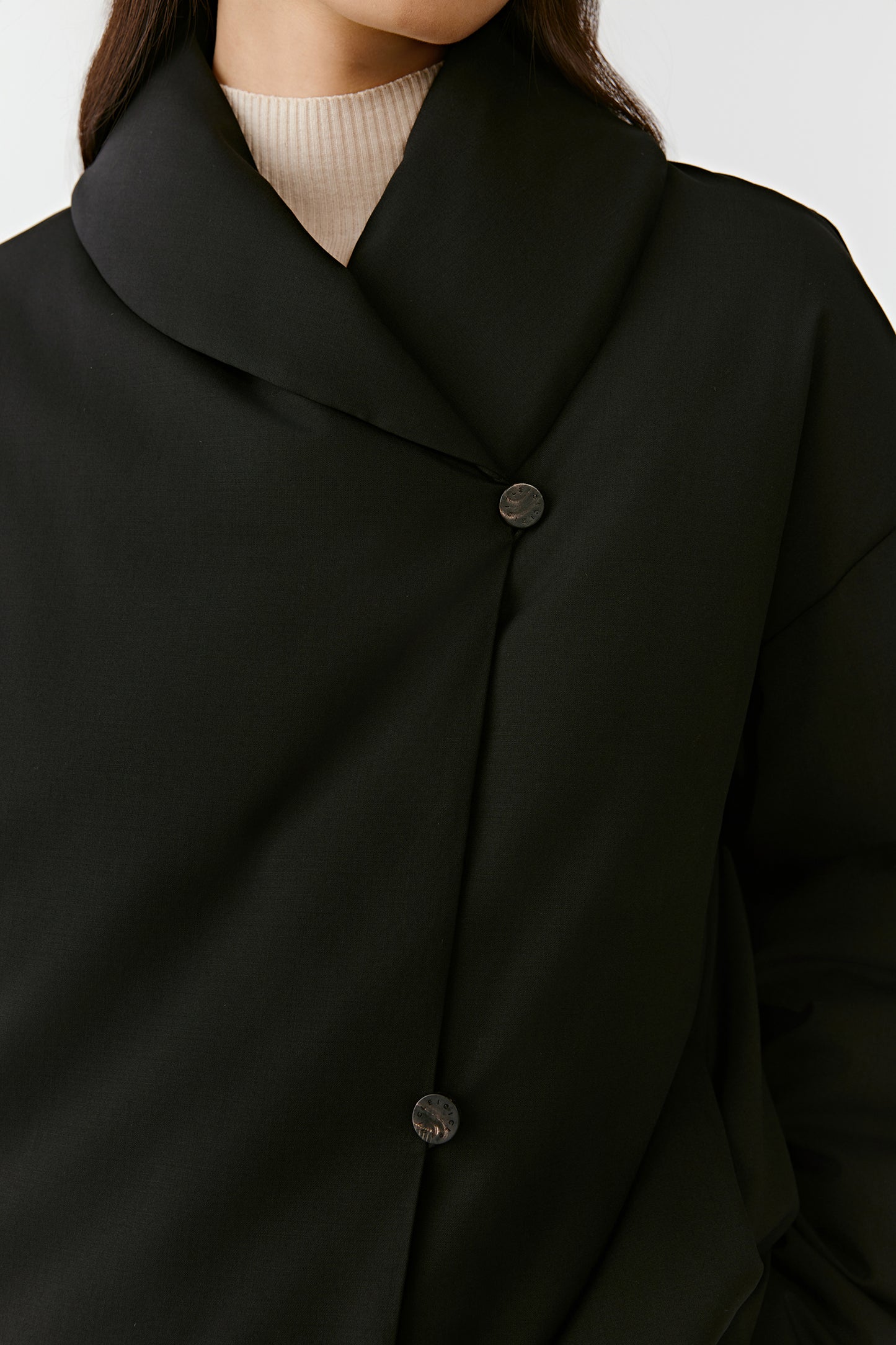 Detail of the wide collar and refined finish of the short black wool and cashmere coat.
