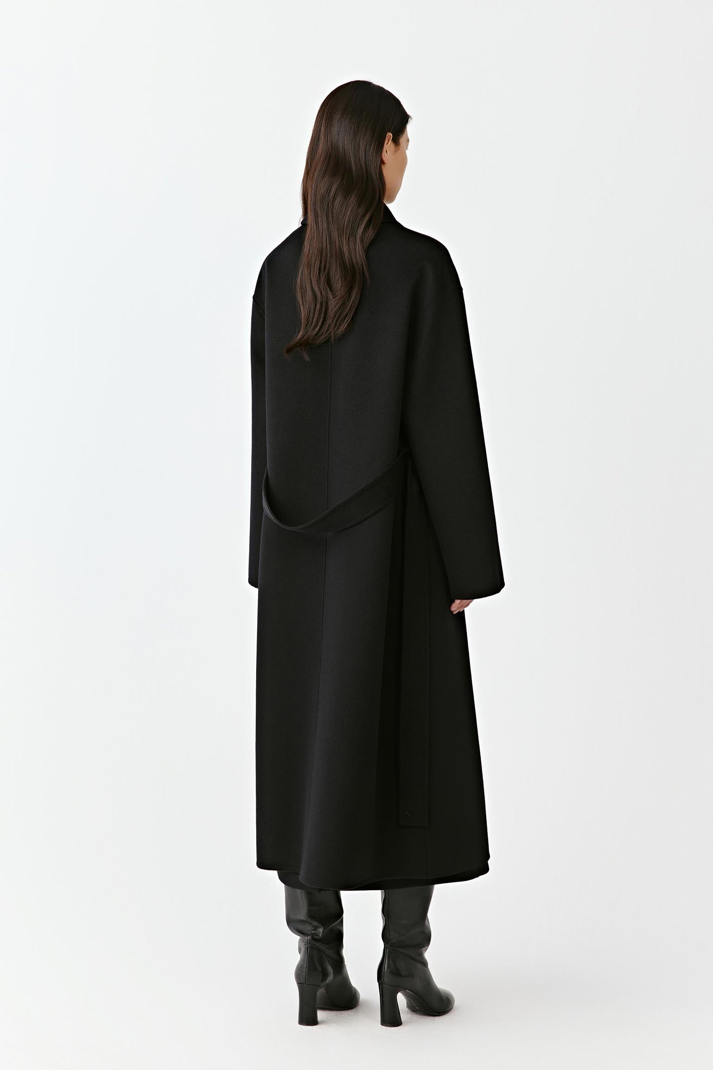 Back view of a long black wool coat with belted waist on a light background