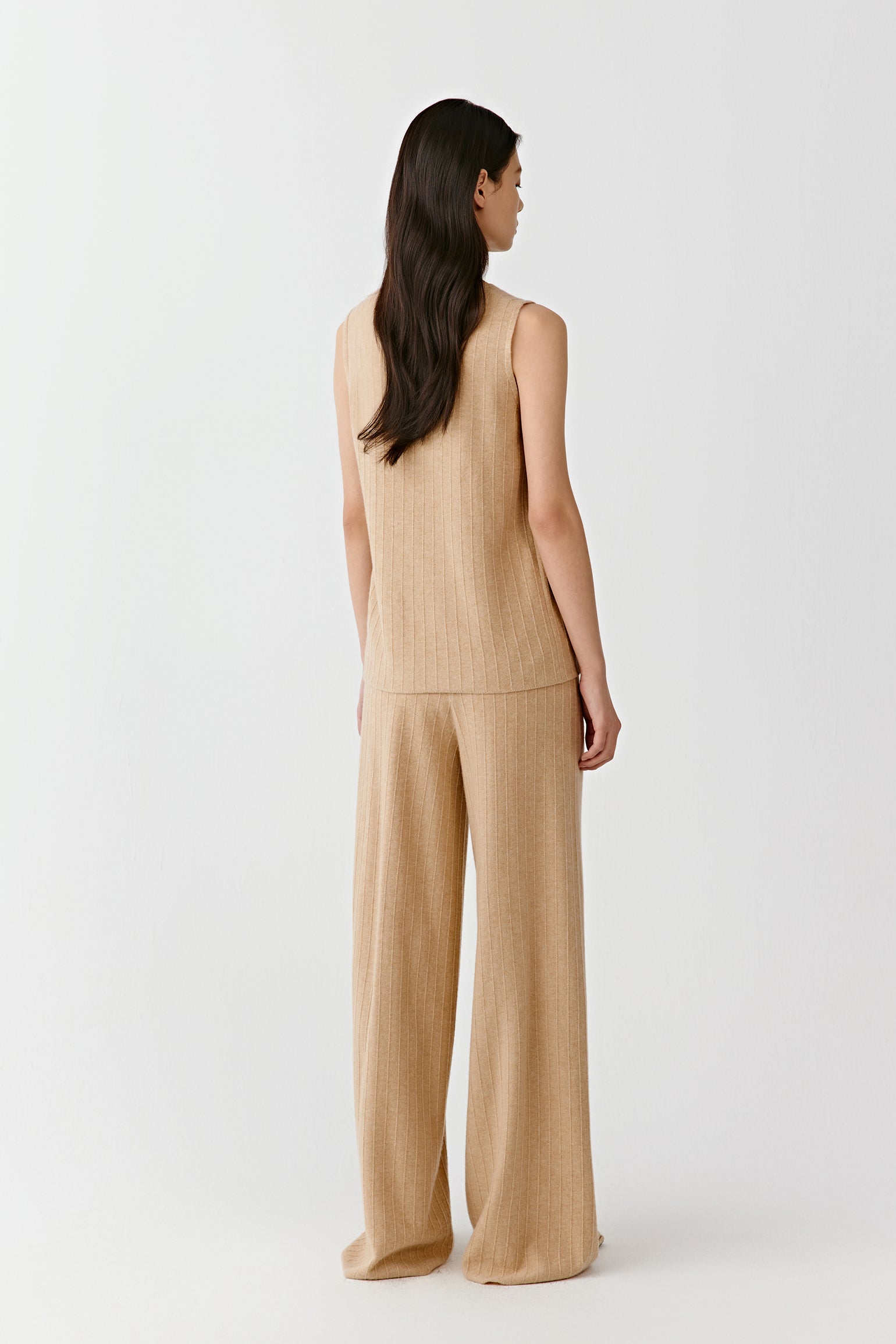 Back view of a sleeveless beige knit top and matching pants on a light background
