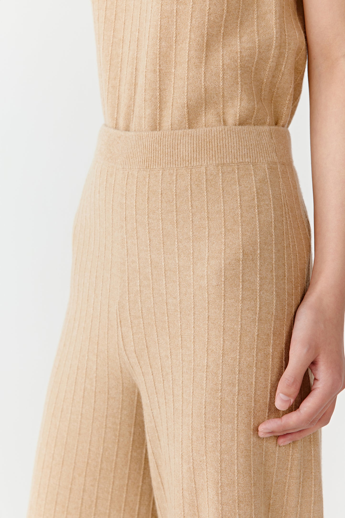 Close-up of beige knit pants waist and ribbed texture on a light background